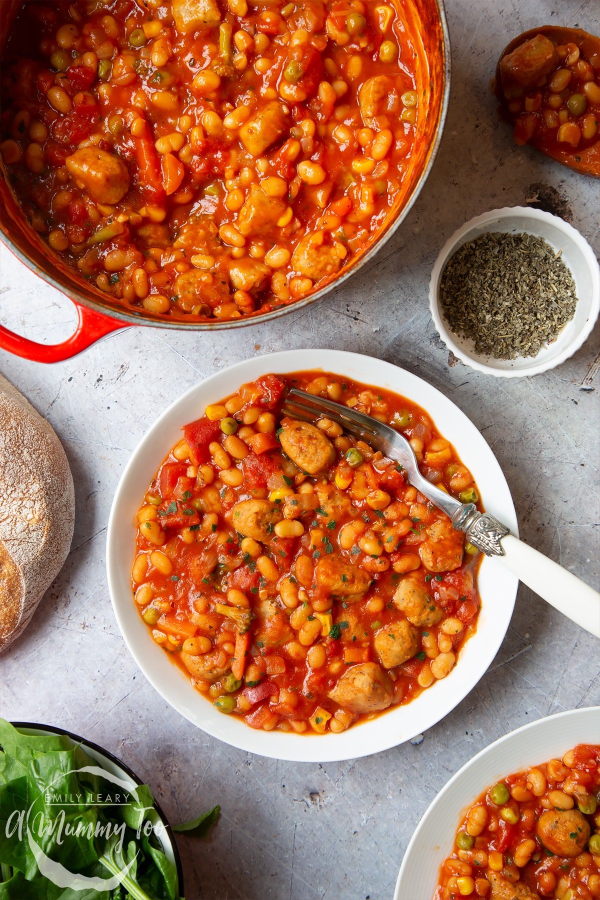 Veggie sausage and bean casserole served into a shallow white bowl. A fork rests in the bowl.