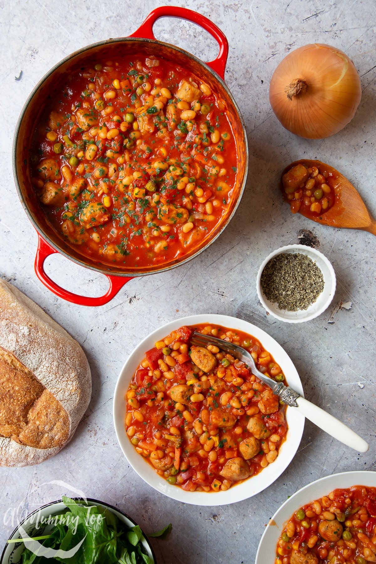 Veggie sausage and bean casserole served into a shallow white bowl. A fork rests in the bowl. The large casserole pot is also shown.