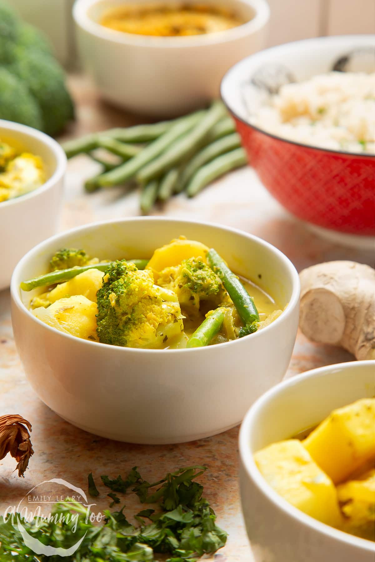 Vegetarian yellow curry served to small white bowls. A bowl of rice is shown in the background.