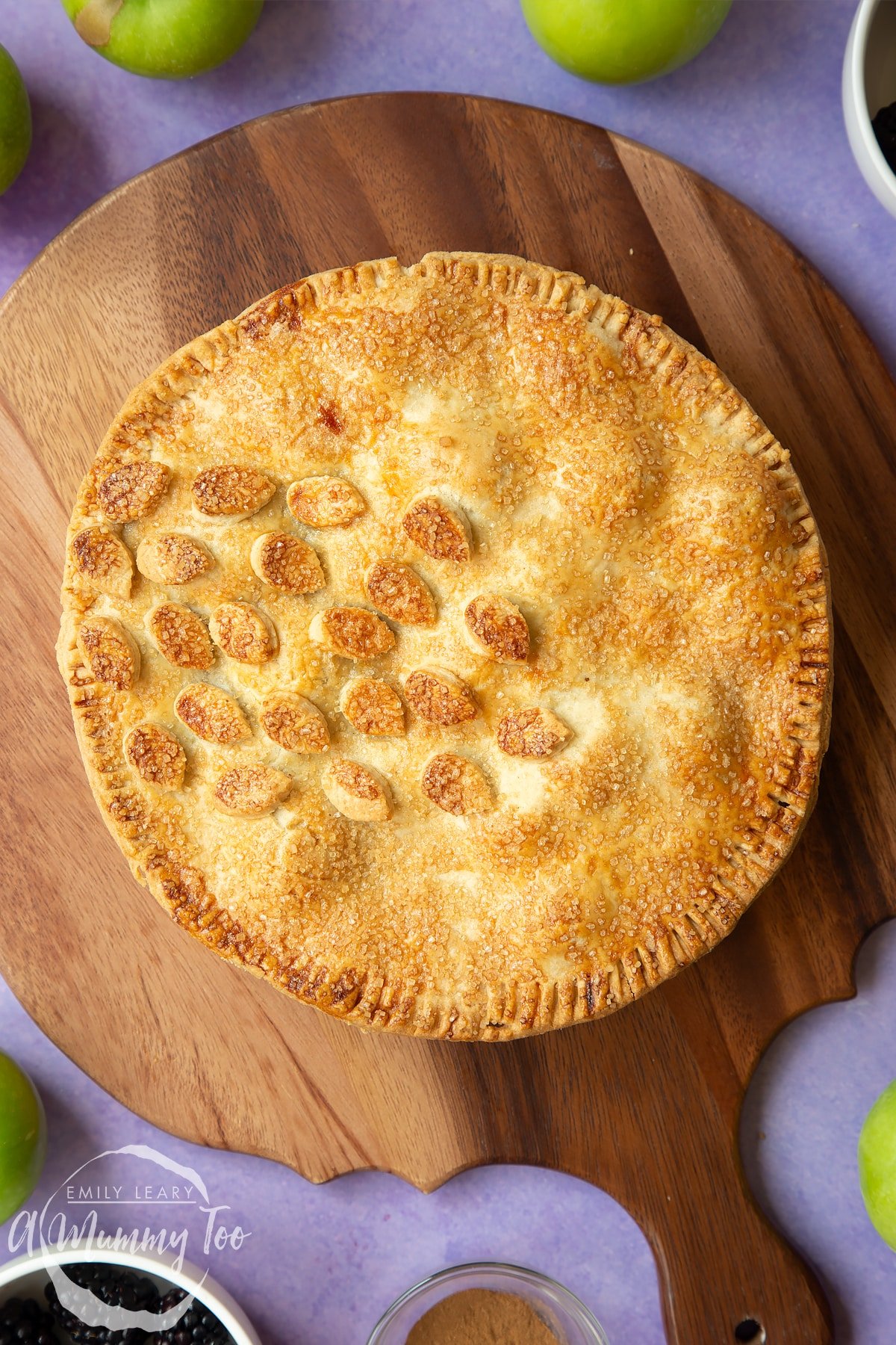 An apple and blackberry pie on a round wooden board.