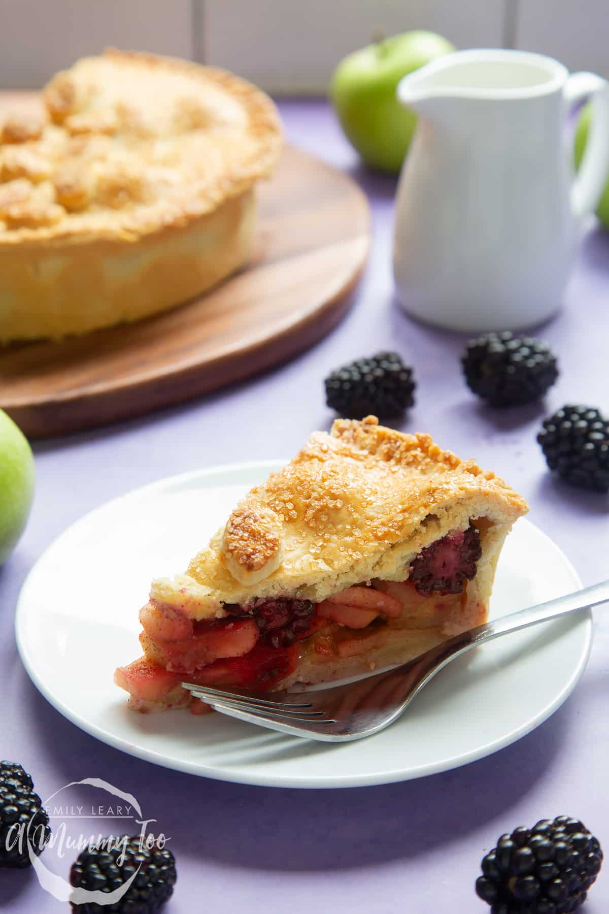 A slice of apple and blackberry pie on a white plate with a fork.