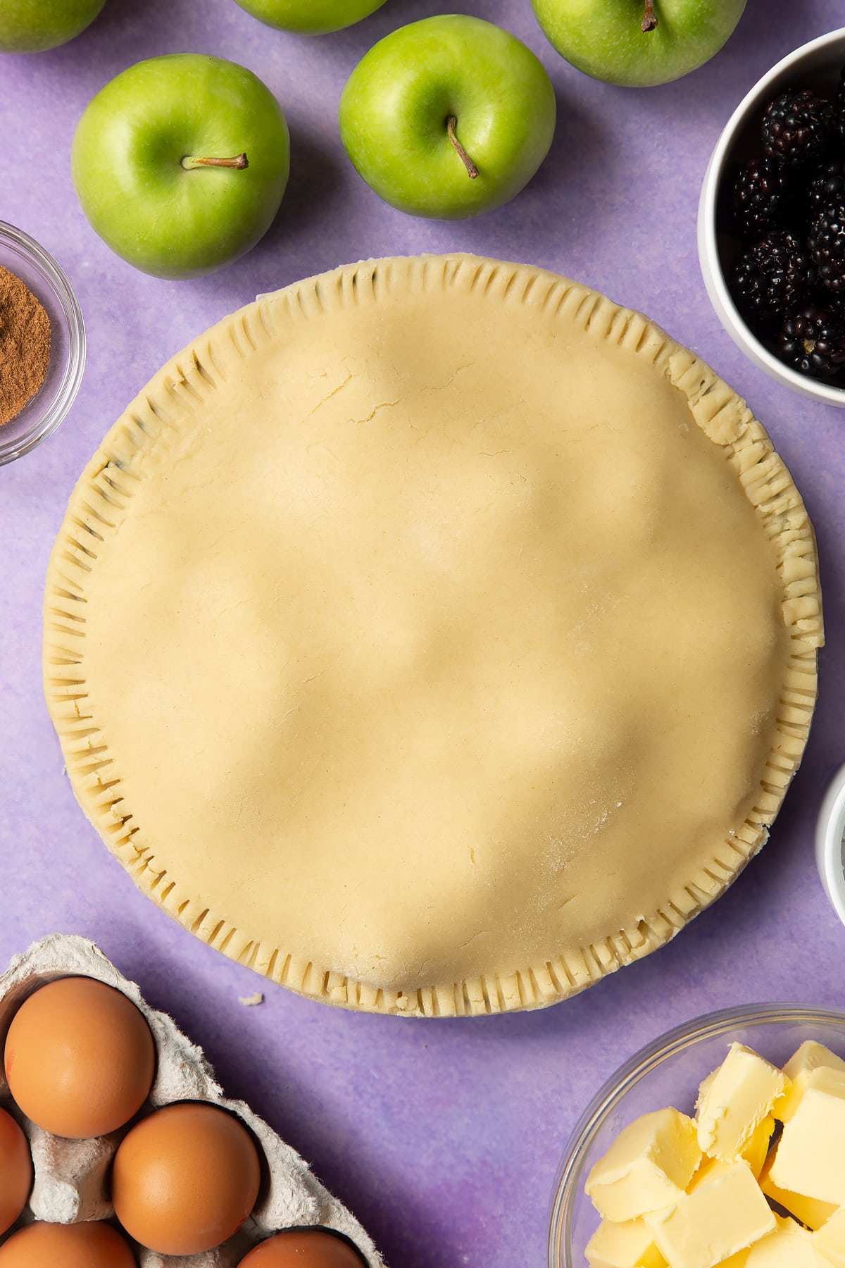 A raw apple and blackberry pie in a tin.