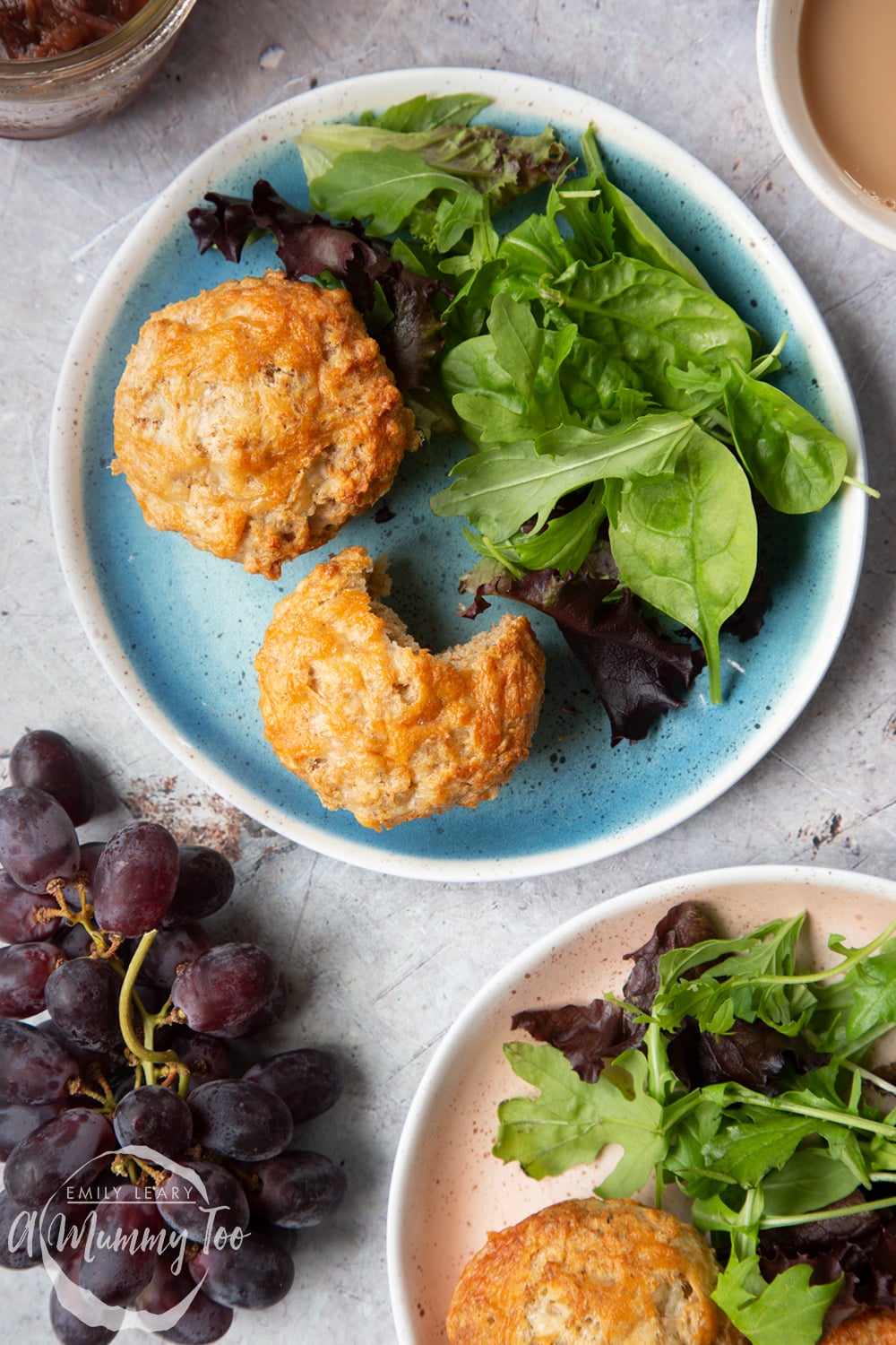 Easy cheese muffins served to two plates with leafy salad. One has a bite out of it.