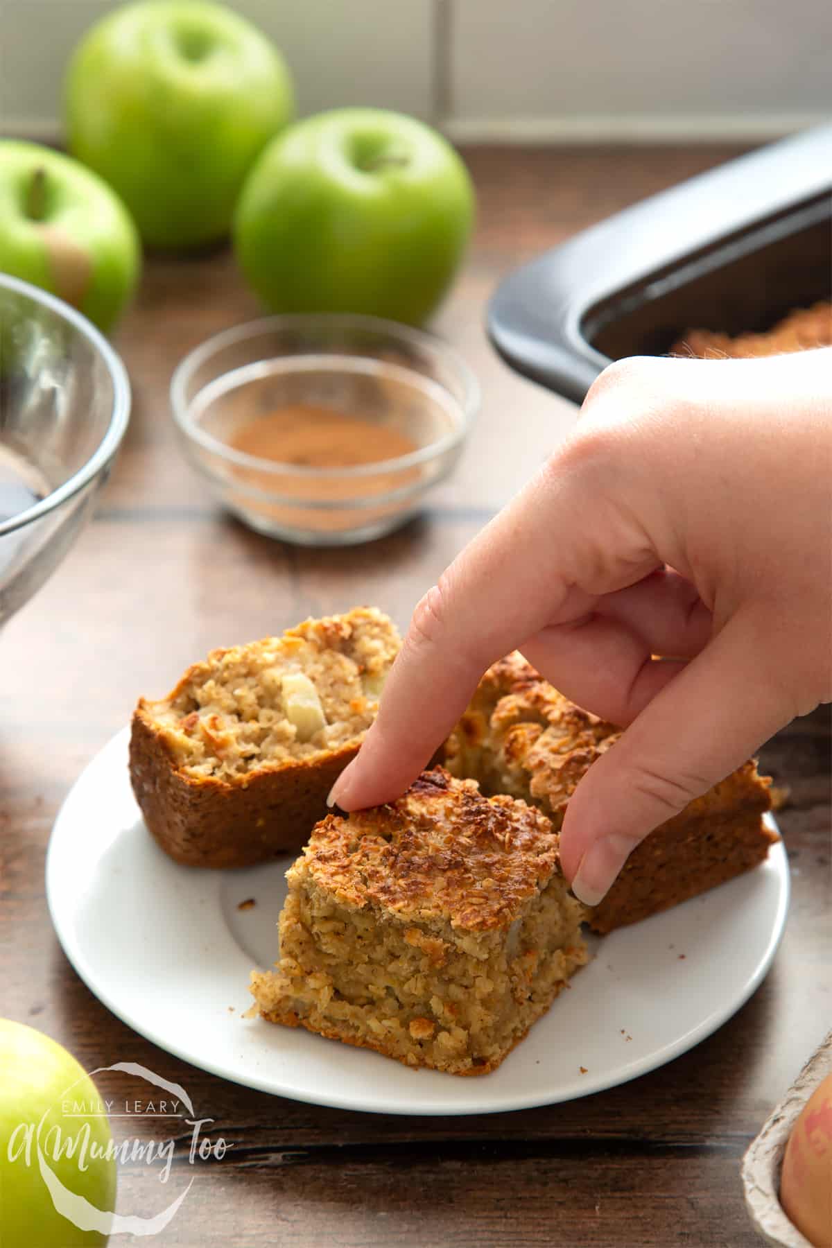 Freshly baked porridge squares cut into 16 pieces. A hand reaches to take a piece.
