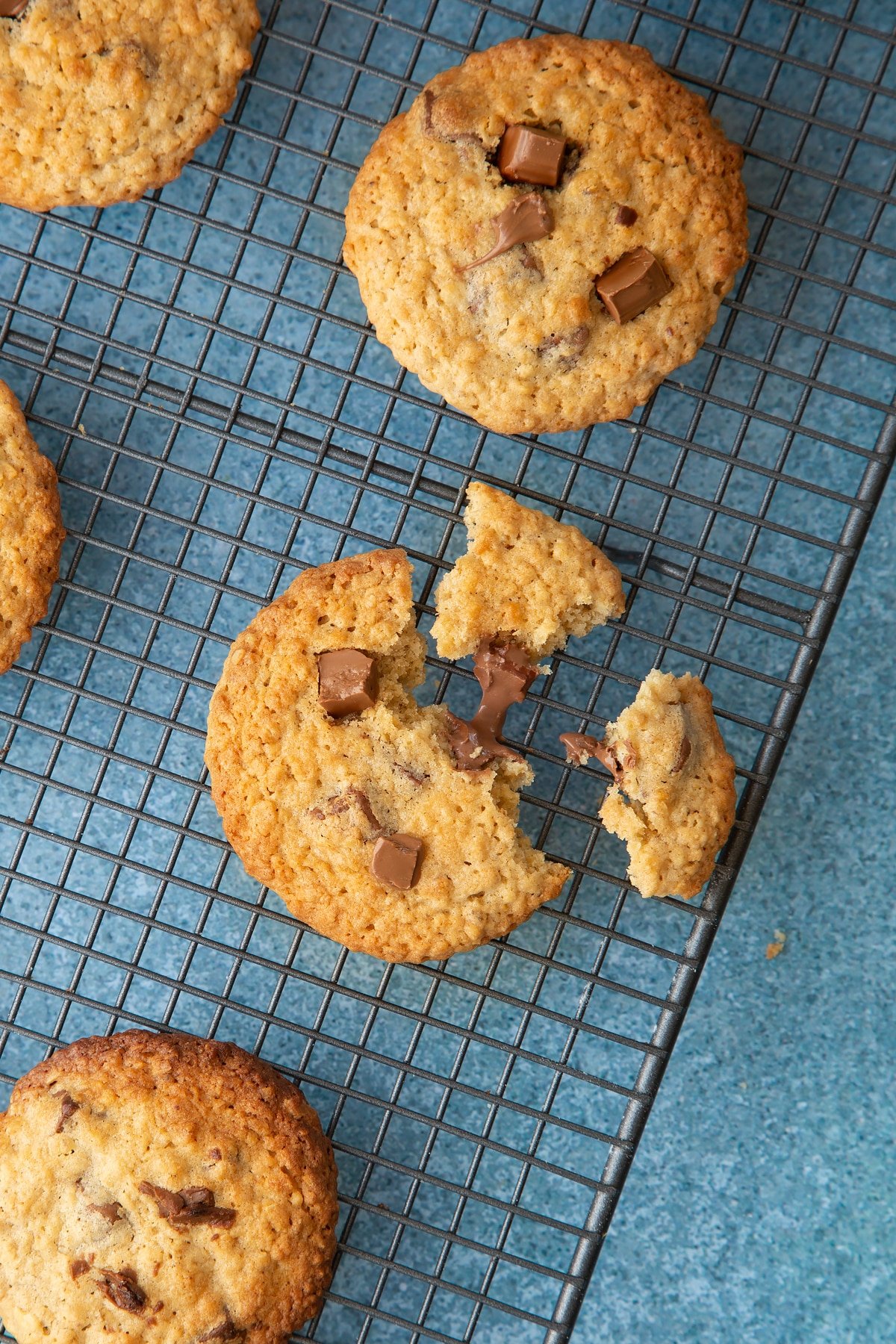 Close up of cookie monster cookies cooling on a wire rack. One cookie is broken into pieces.