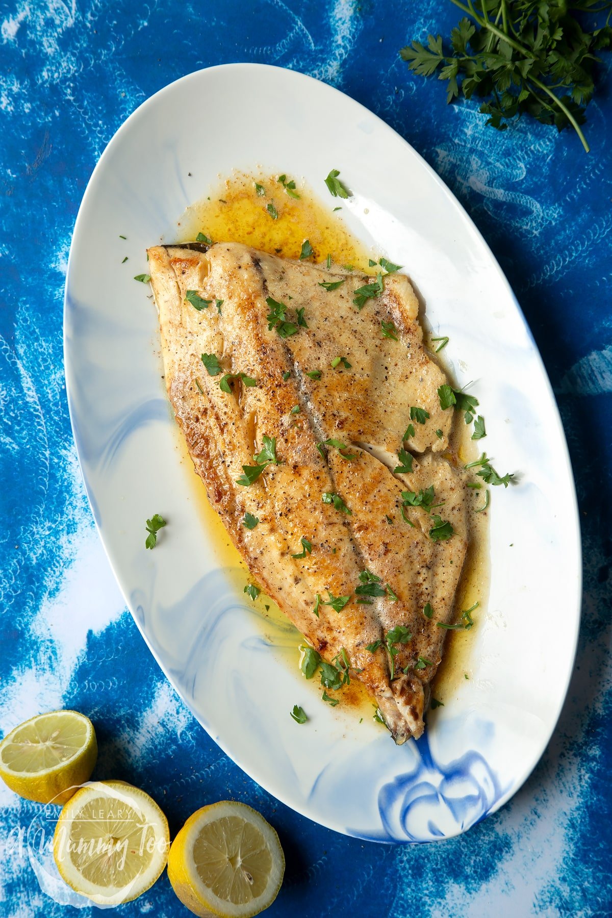 Pan-fried Yellowtail on an oval serving dish. The fish fillet is scattered with parsley.