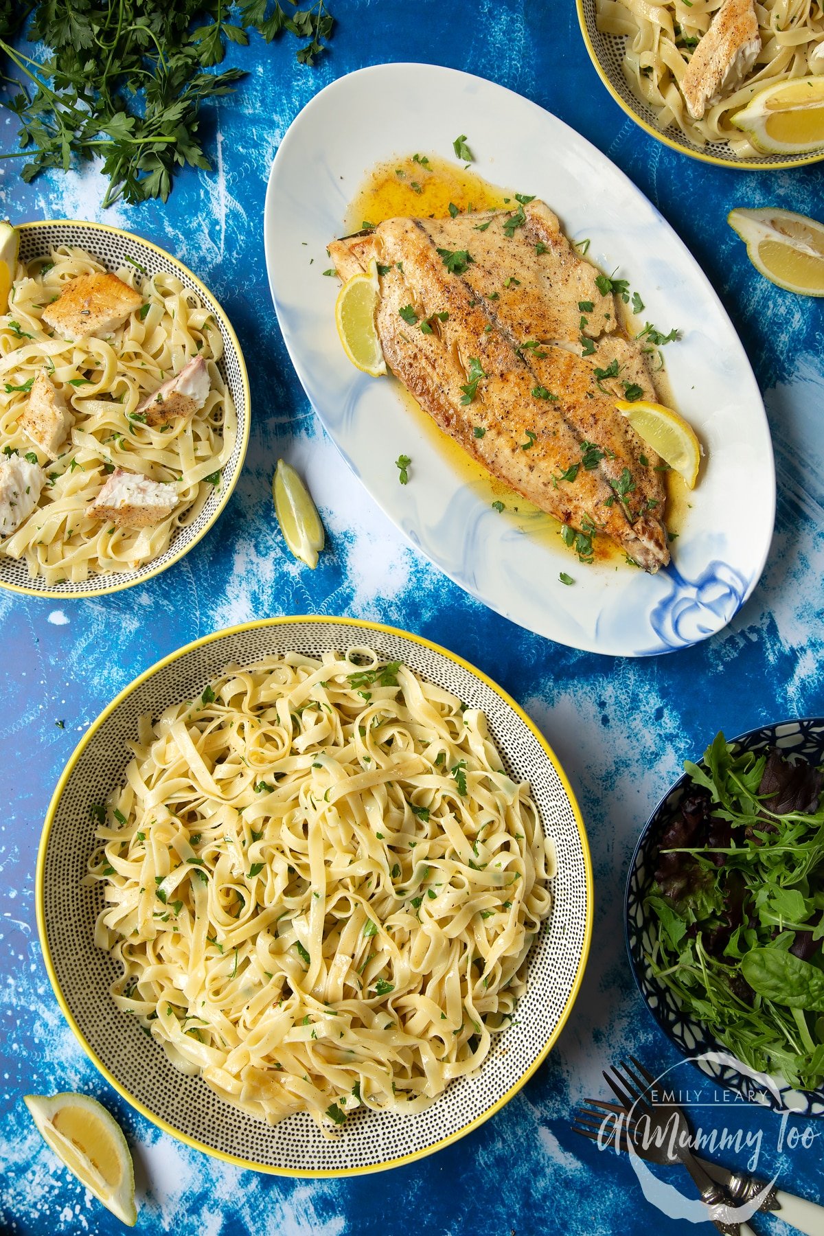 Pan-fried Yellowtail on a large oval serving dish. A large serving bowl of herby tagliatelle is also shown.