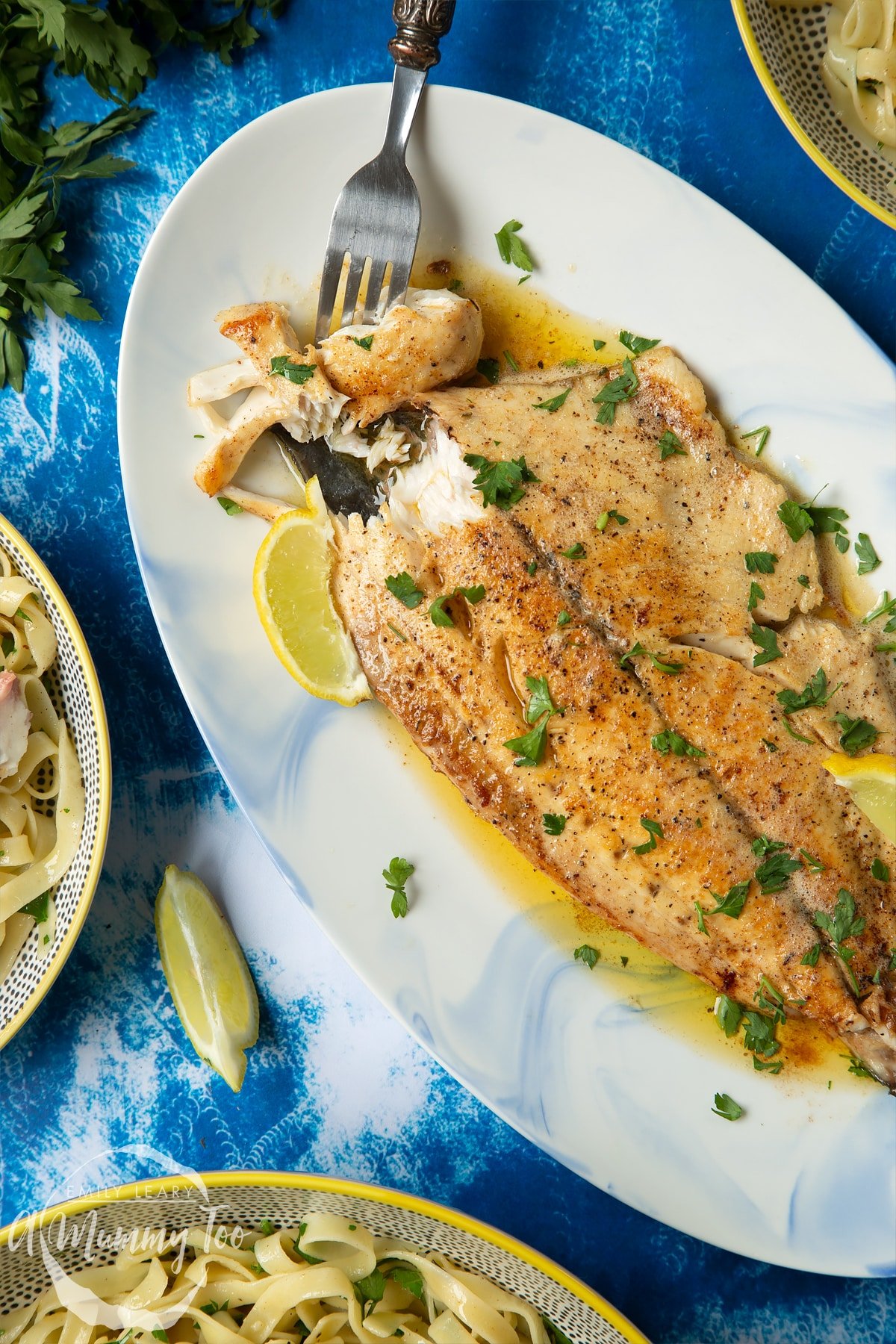 Pan-fried Yellowtail on a large oval serving dish. A fork delves into the buttery fish.