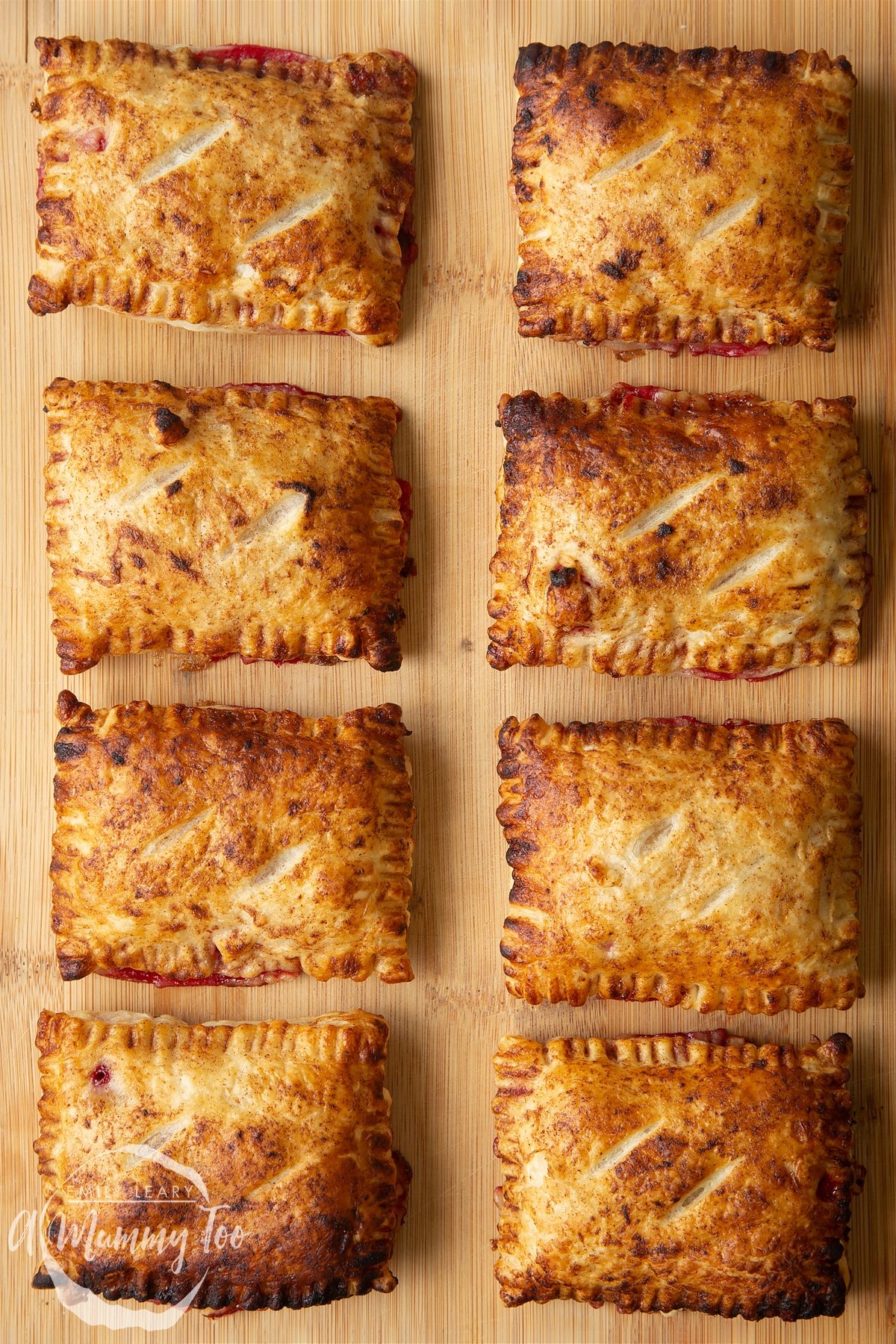 Eight plum pastries on a wooden board. 