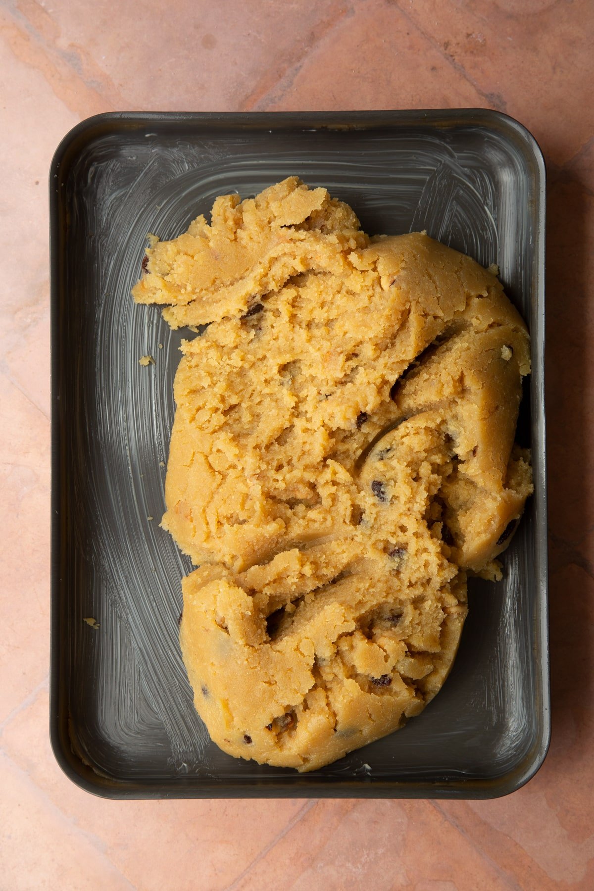 A greased tray with golden semolina cake dough.