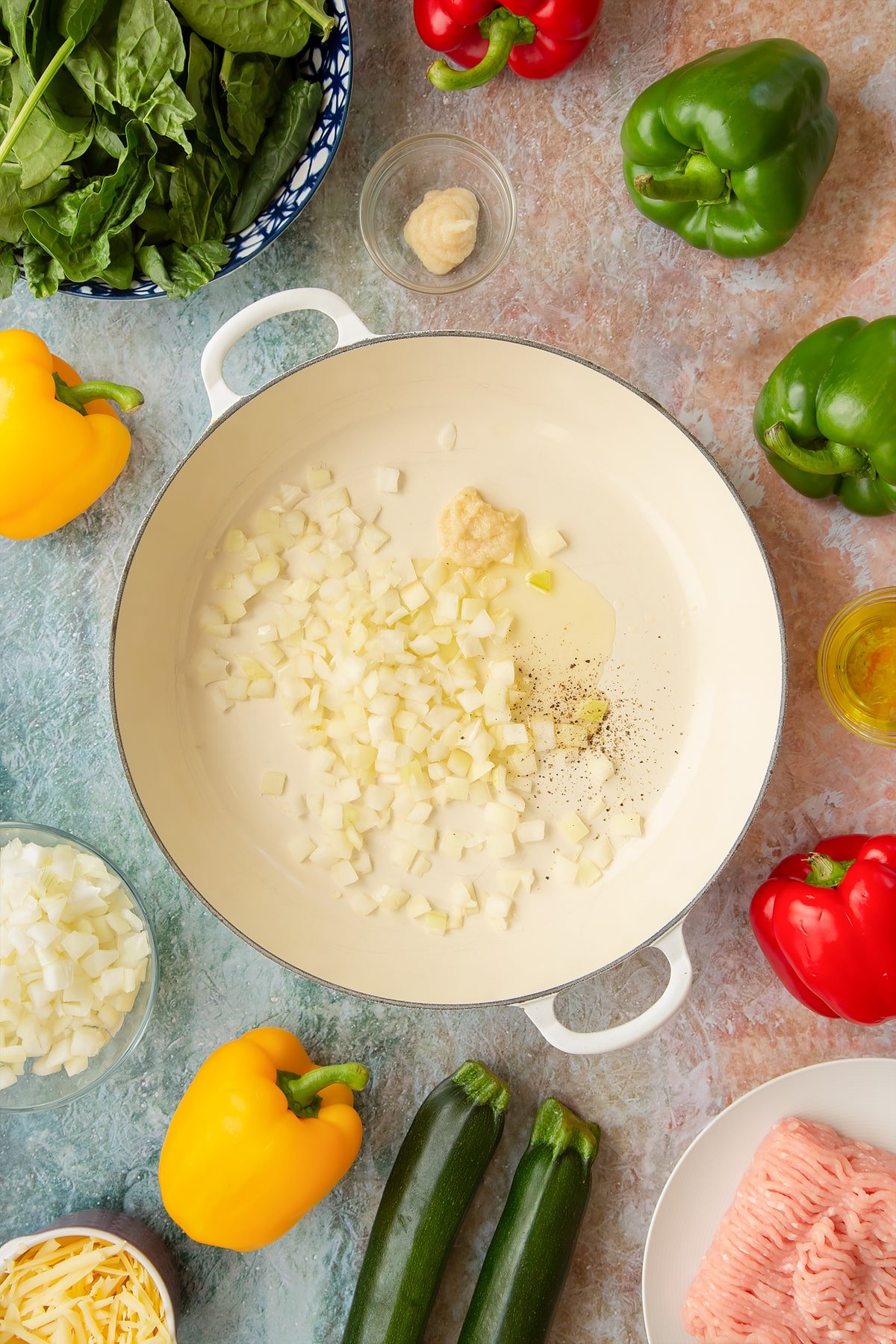 Oil, onion, garlic, salt and pepper in a large shallow pan. Ingredients to make baked bean stuffed peppers surround the pan.