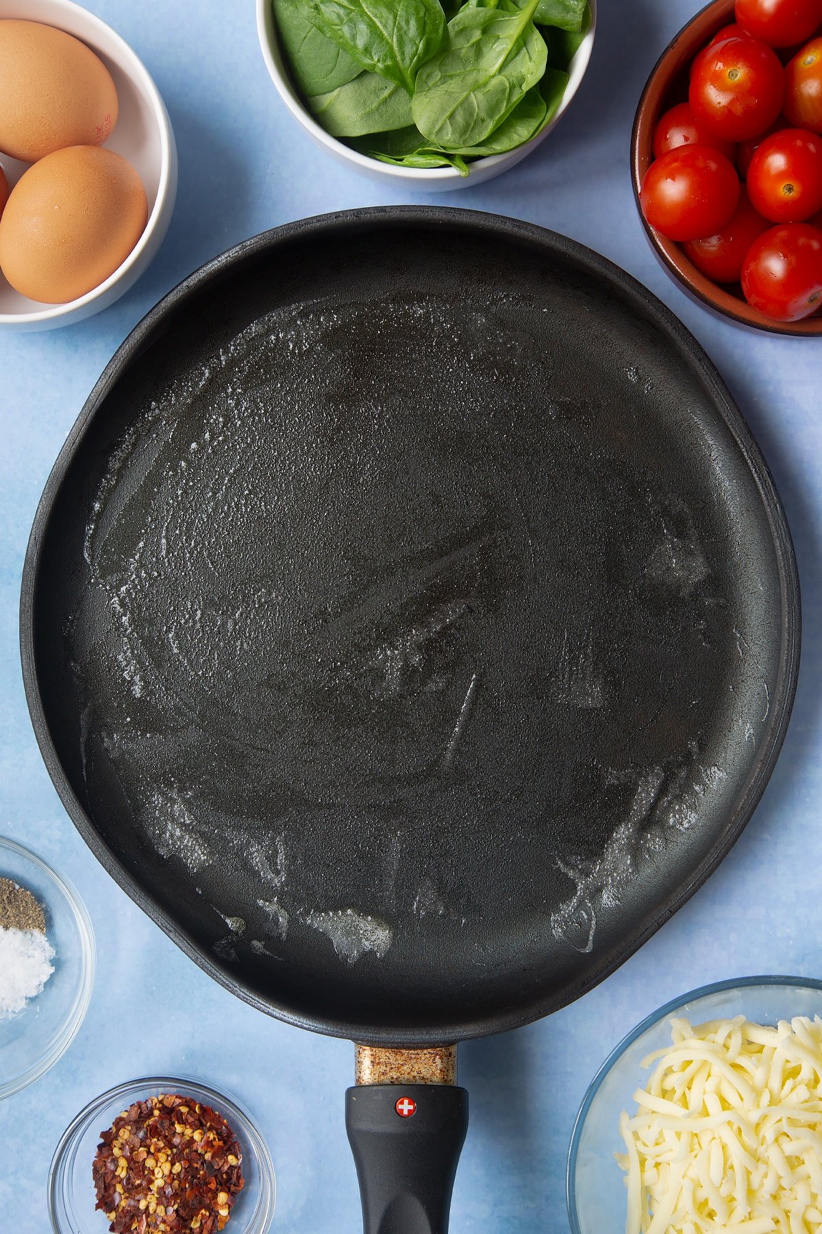 Butter melted in a crepe pan. Ingredients to make buckwheat galettes surround the pan.