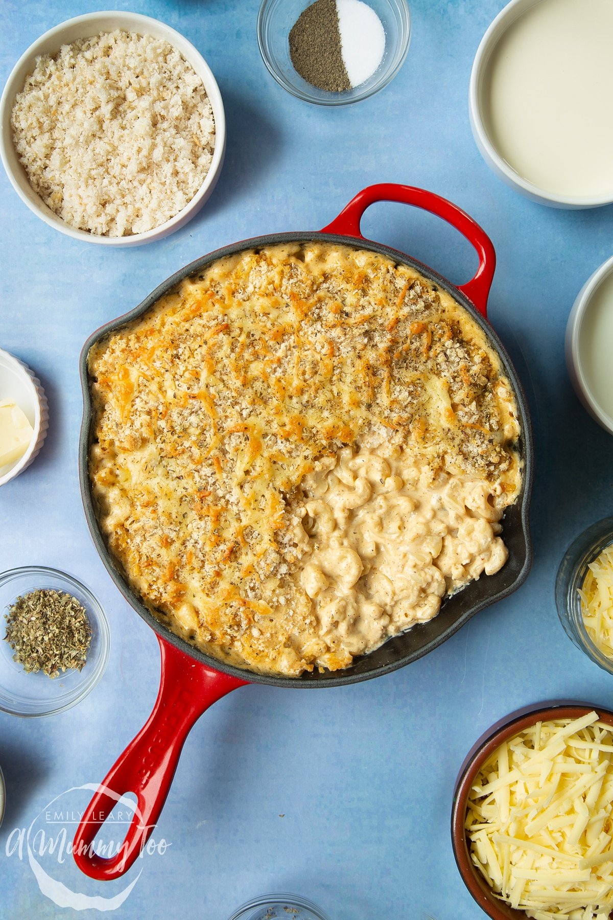 Freshly baked garlic and herb mac and cheese in a skillet. Some of the pasta has been served, showing the creamy pasta beneath the herby crumb.