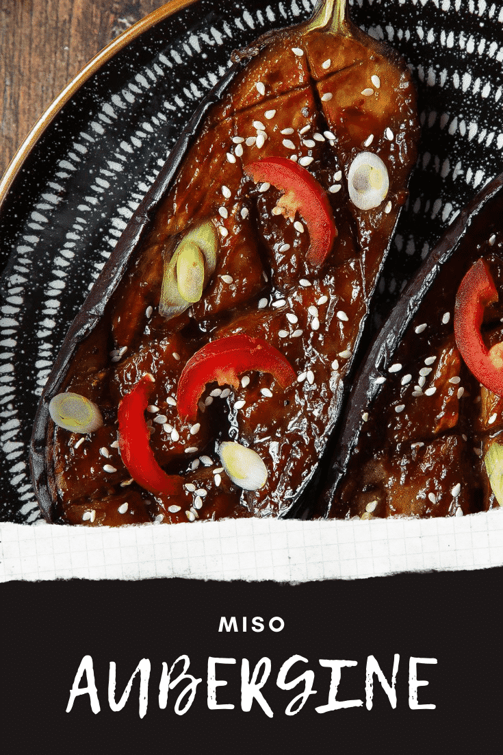 Close up of miso aubergine on a plate, topped with chilli, springs onions and sesame seeds. Caption reads: miso aubergine