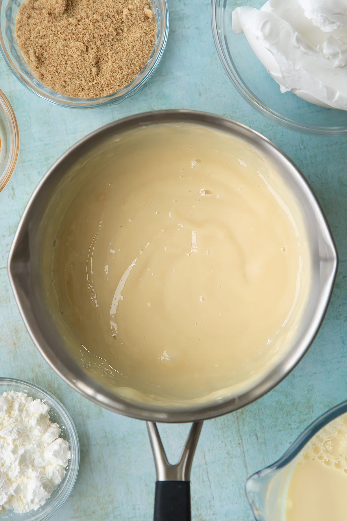 Vegan custard in a pan. Ingredients to make vegan custard surround the pan.