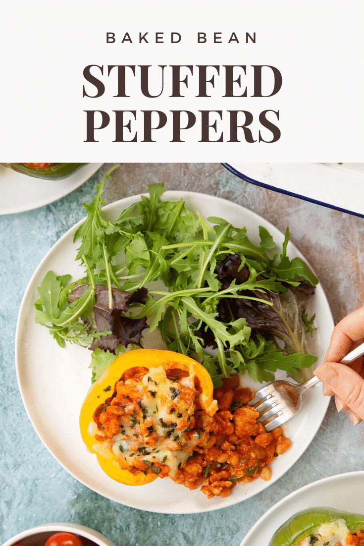 A yellow stuffed pepper served on a white plate with the filling spilling out. A fork delves in. Caption reads: Baked bean stuffed peppers