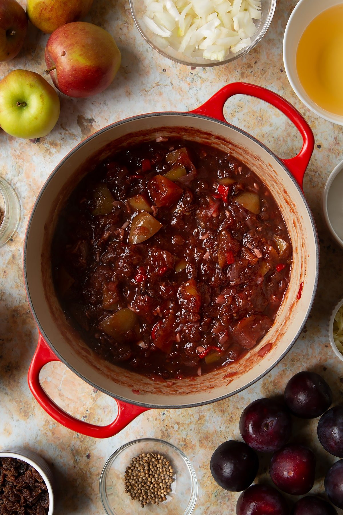 Fruit chutney in a large pan. Ingredients to make a fruit chutney recipe surround the pan.