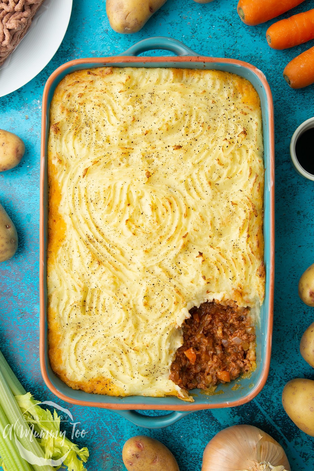 Vegan cottage pie in a roasting dish. A little bit of the pie has been served.