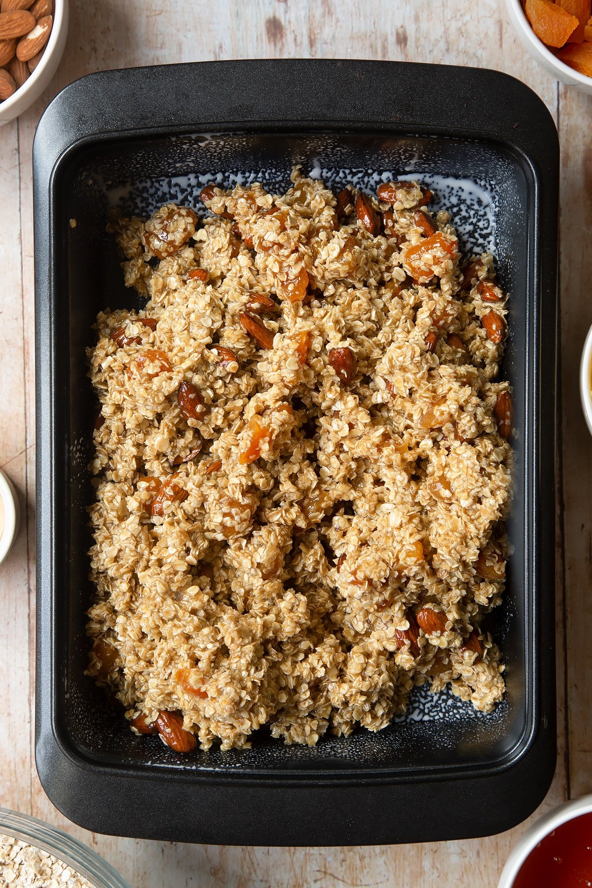 Overhead shot of oat mixture in a black baking tin