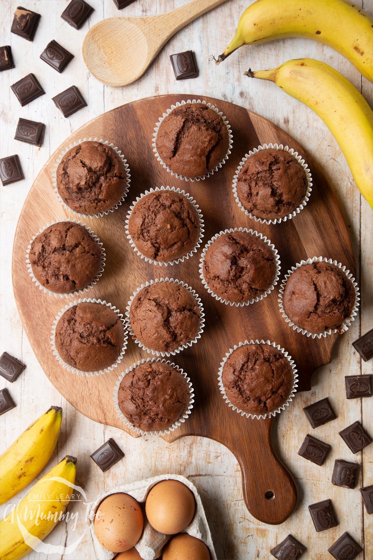 Overhead shot of Banana and chocolate muffins served on a wooden plate with a mummy too logo in the lower-left corner
