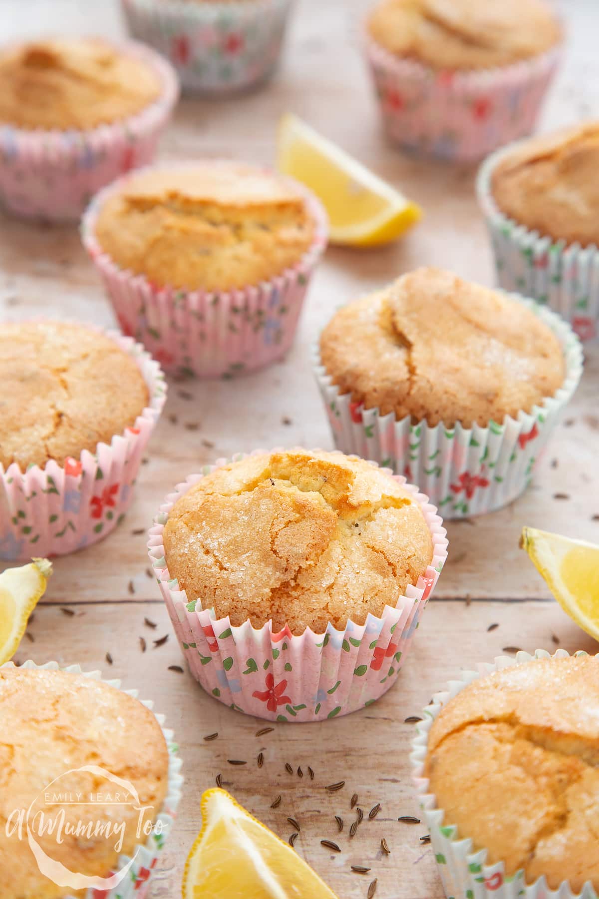 Front angle shot of caraway seed muffin with lemons in the side and a mummy too logo in the lower-left corner 