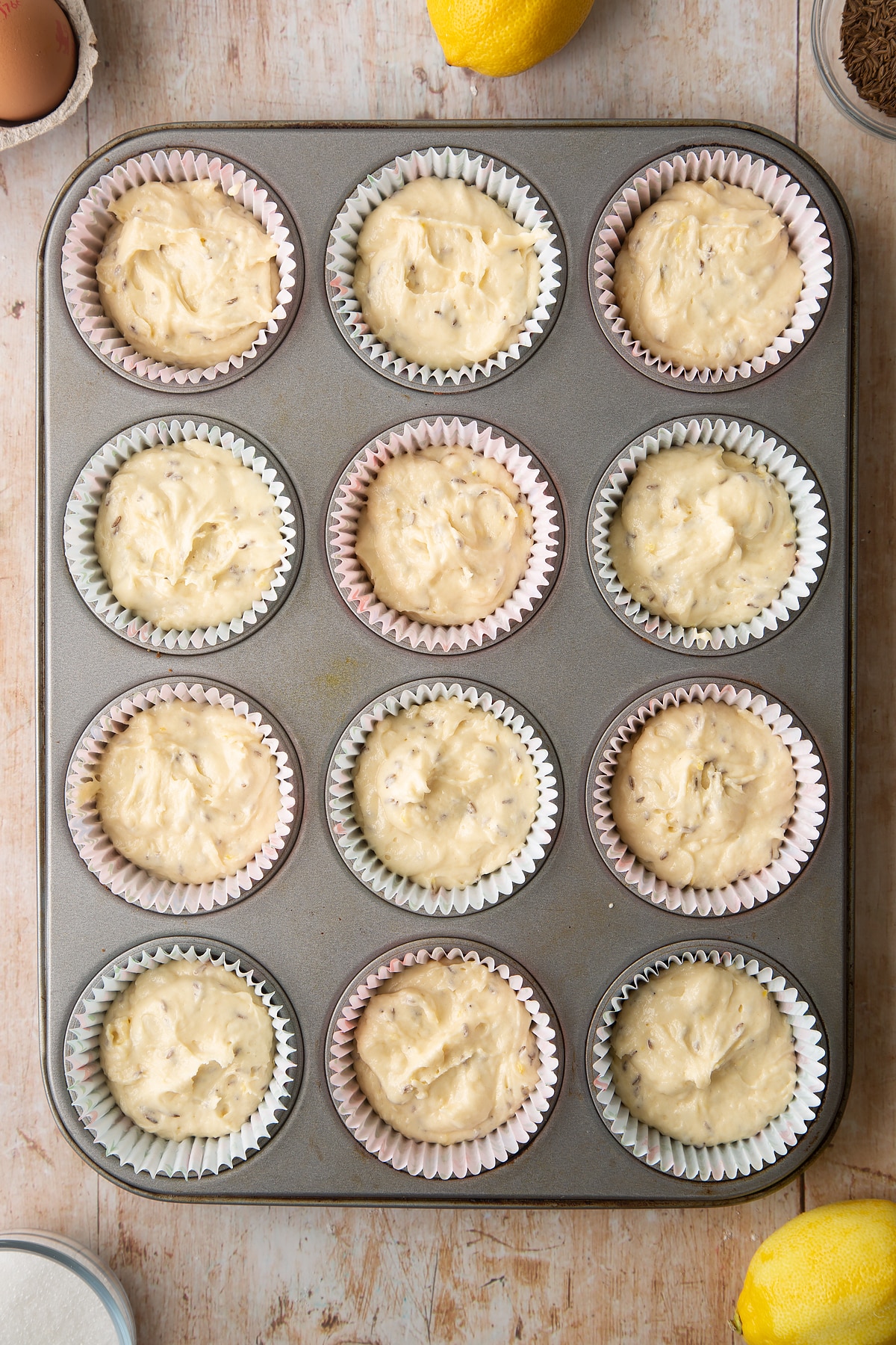 Overhead shot of muffin mix  in a 12 hole muffin tray lined with paper cases  