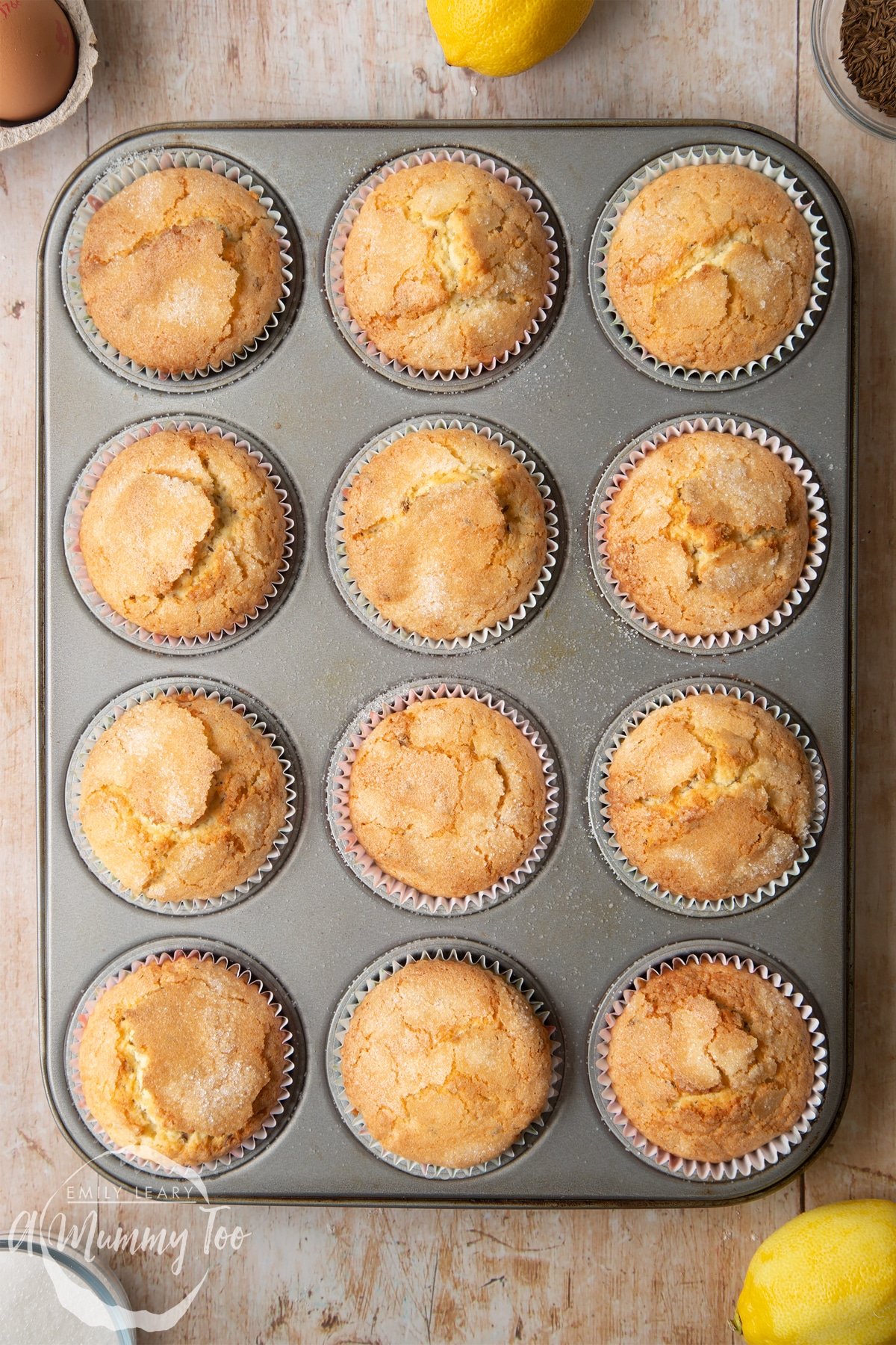 Overhead shot of golden caraway seed muffins in a black muffin tray 