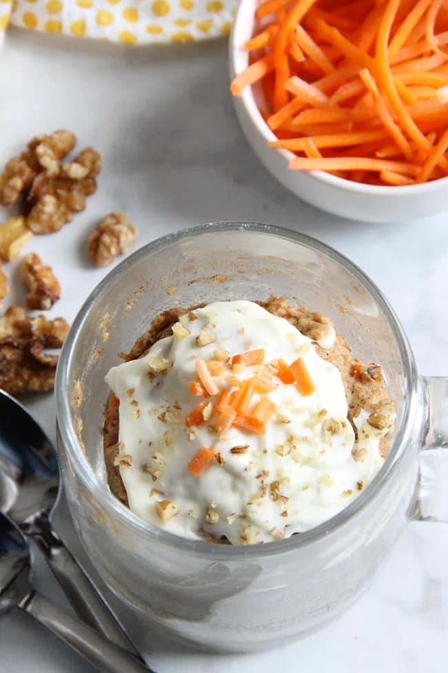 Carrot cake mug cake topped with cream cheese frosting and a little grated carrot.