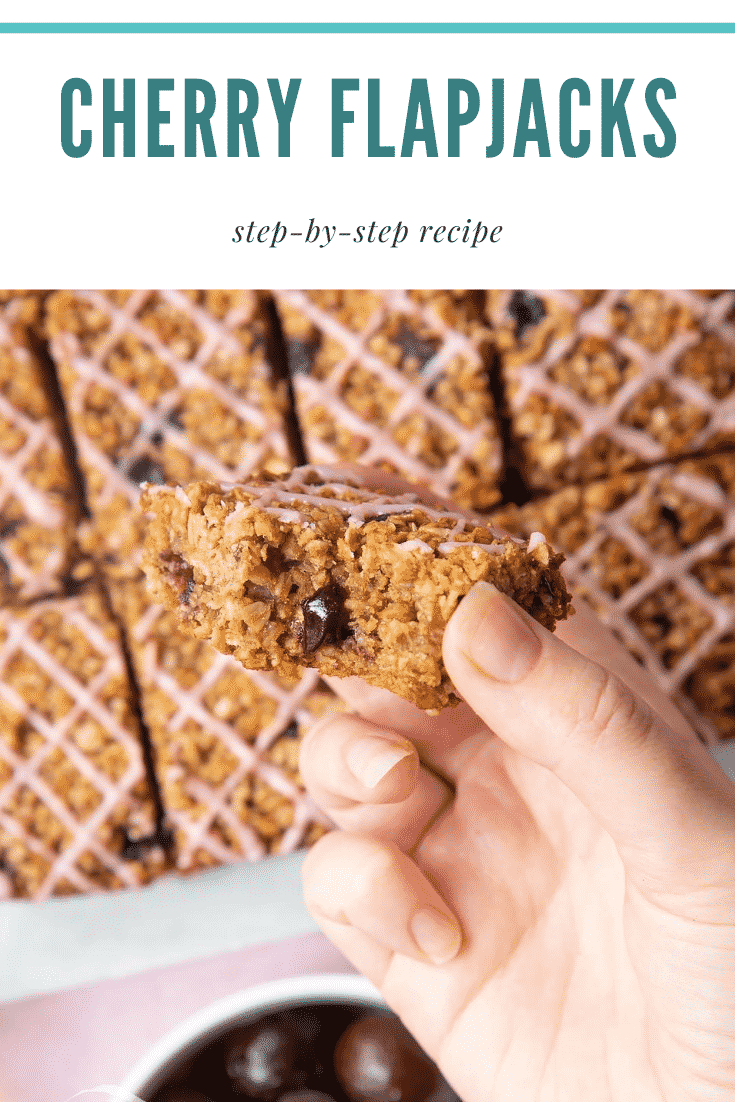 Graphic text STEP-BY-STEP RECIPE CHERRY FLAPJACKS EASY AND DELICIOUS above Overhead shot of a hand holding a cherry flapjack with a mummy too logo in the lower-left corner