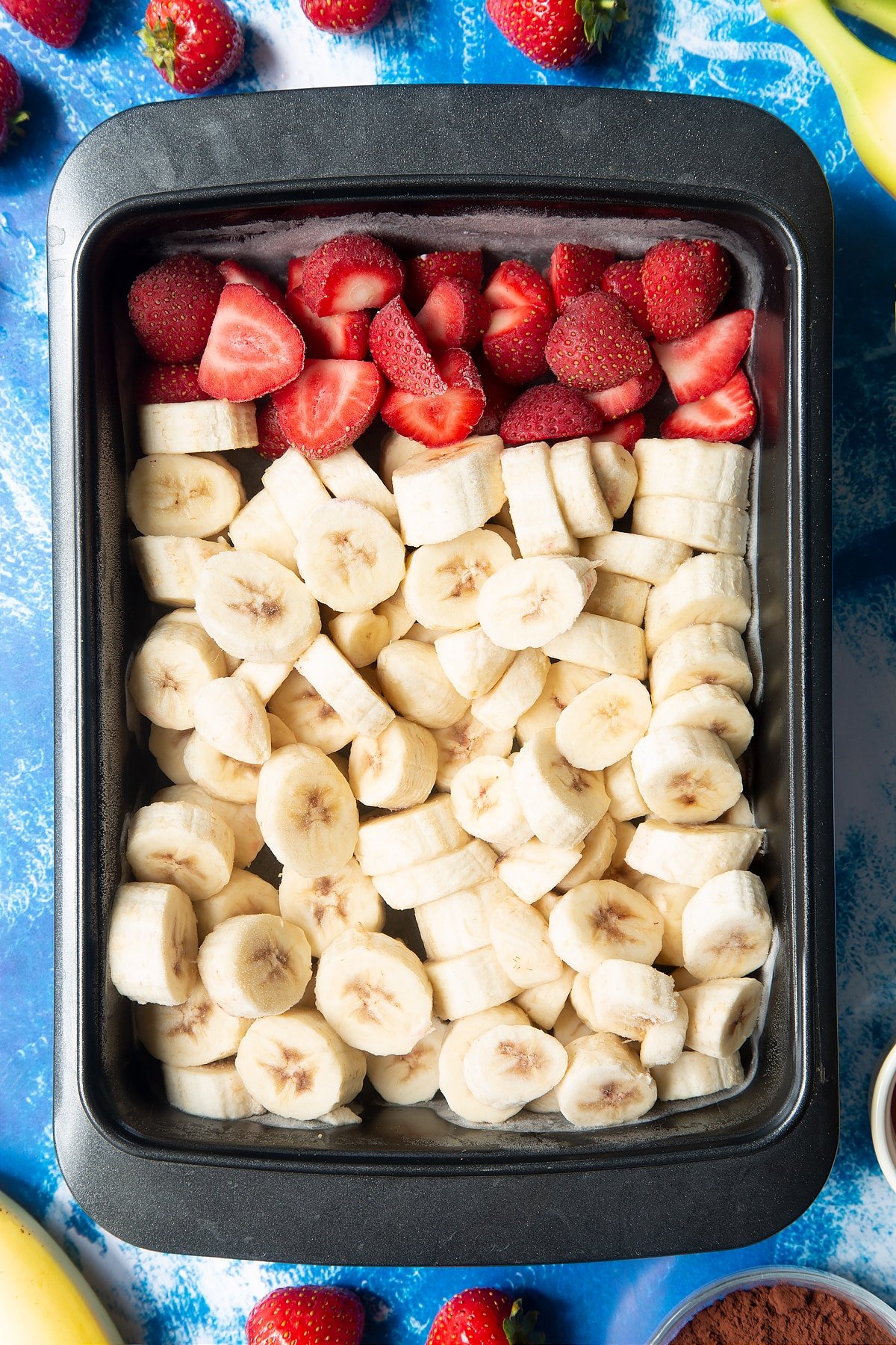 Frozen sliced bananas and strawberries in a tray.