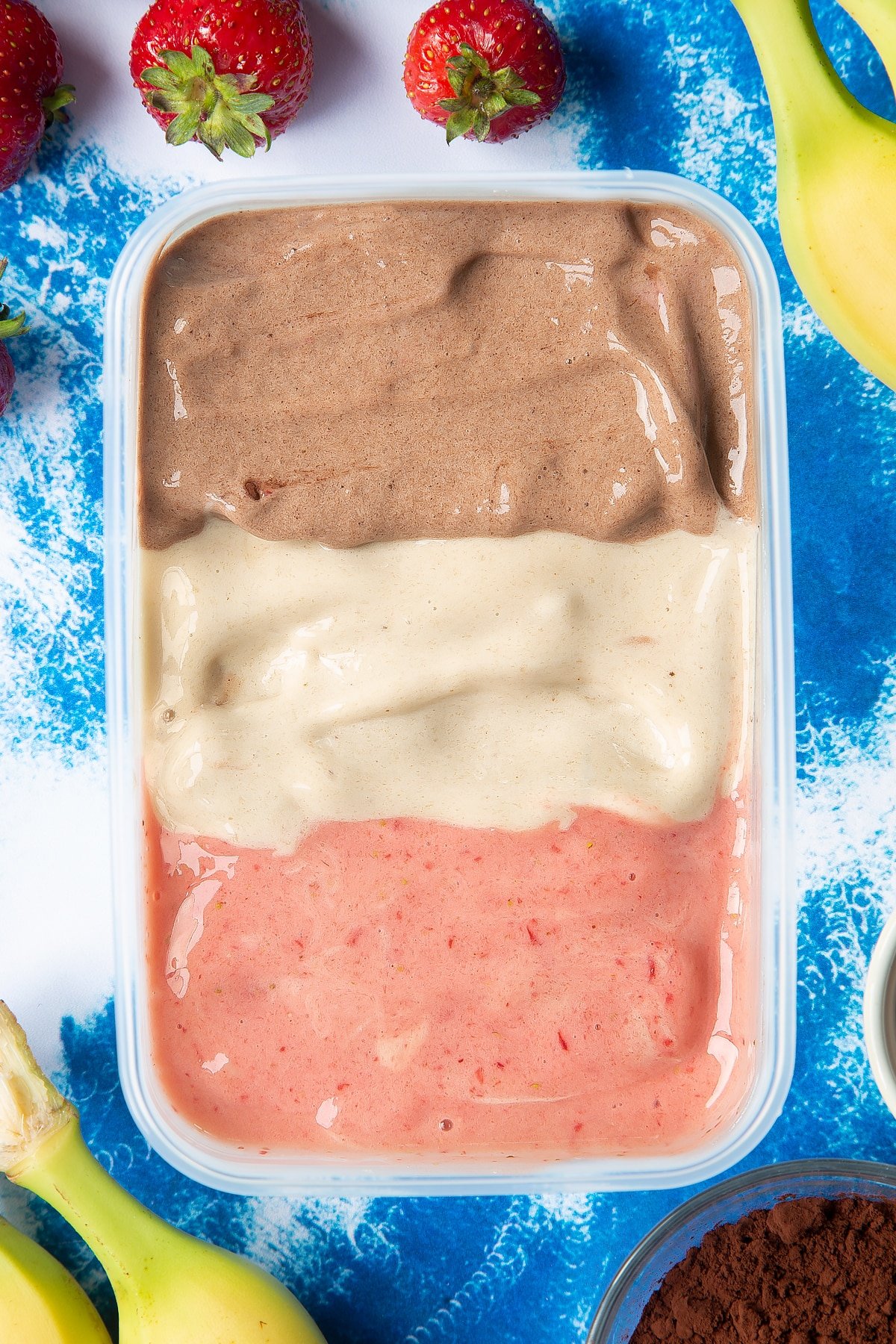Banana ice cream arranged in three rows in a tub - one chocolate, one vanilla and one strawberry.