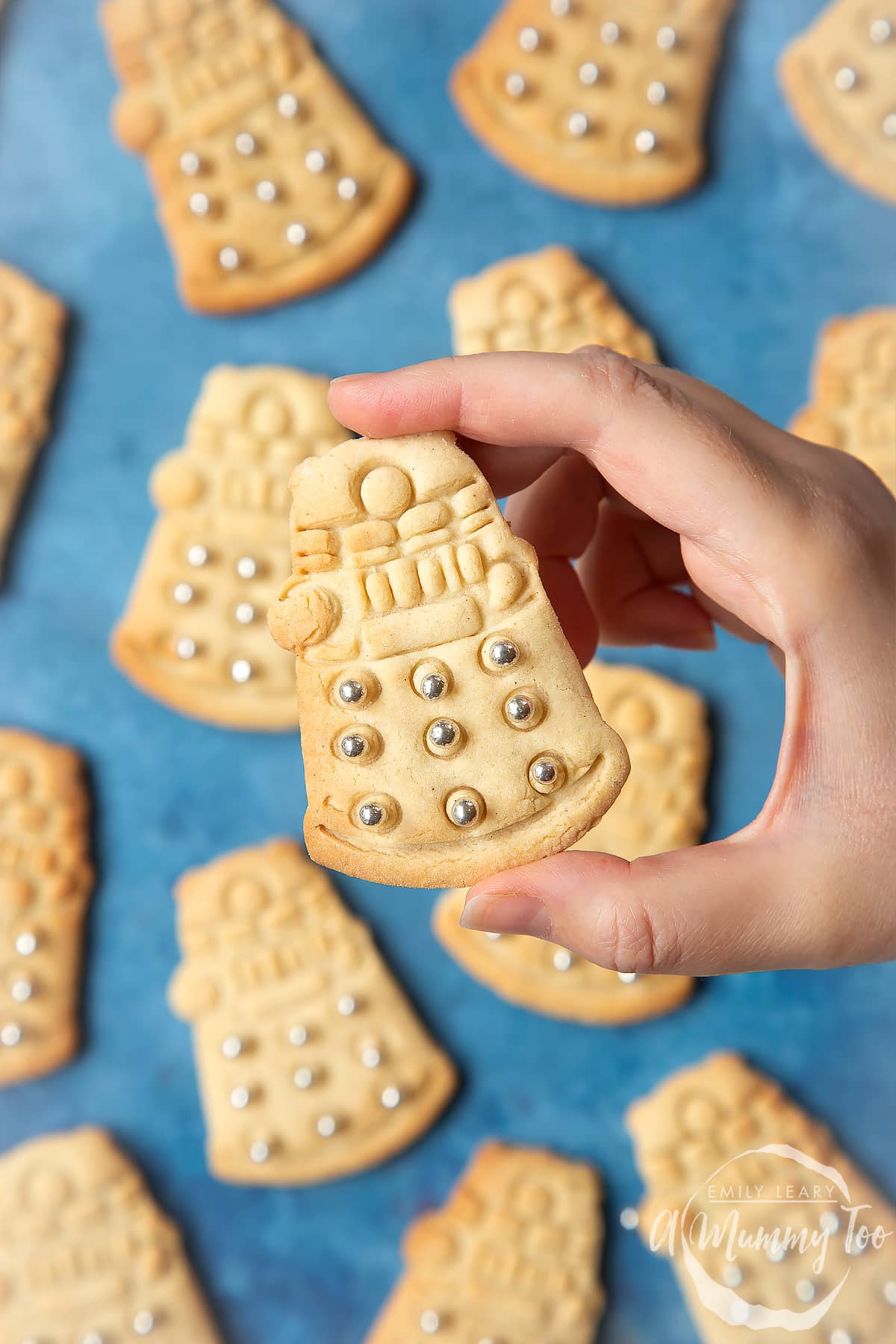 Dalek sugar cookies decorated with silver candy balls. A hand holds one.