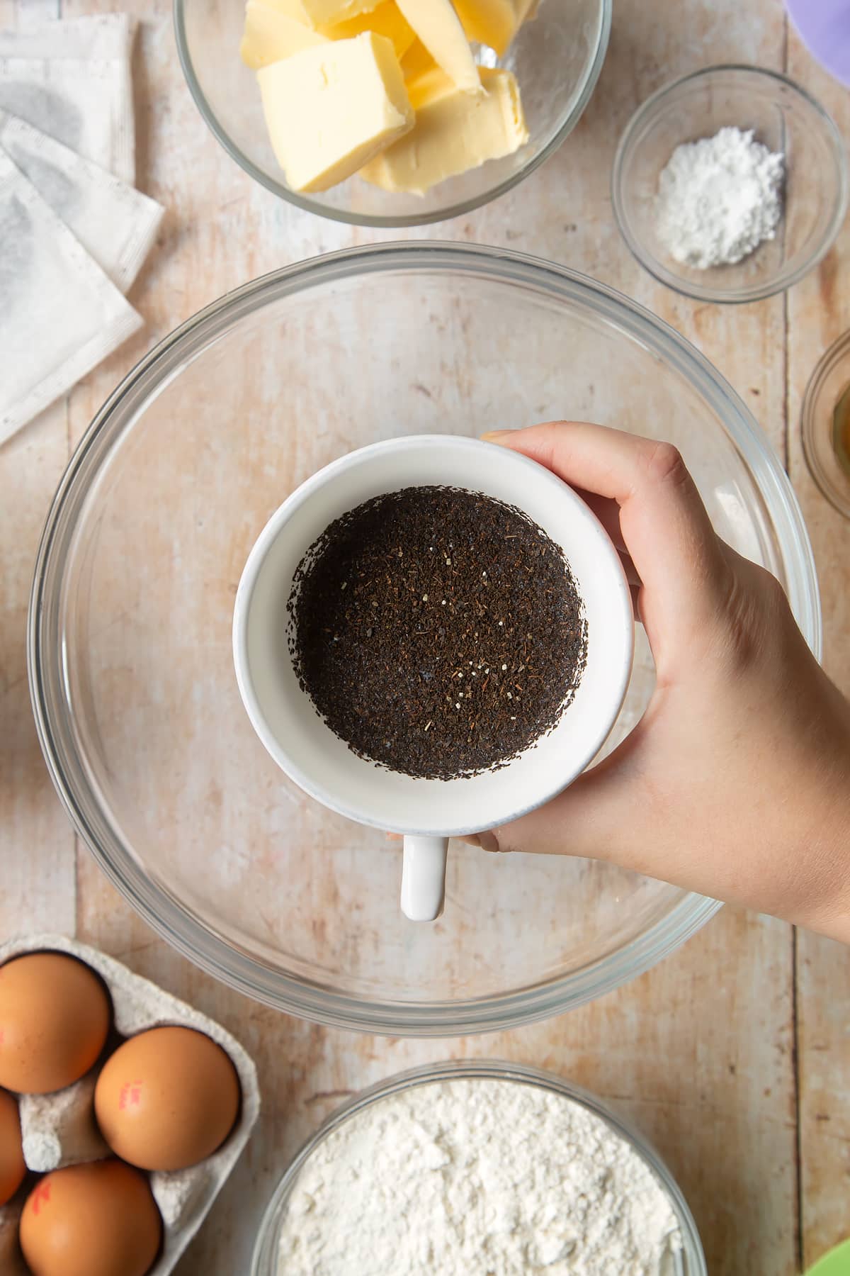 Overhead shot of a hand holding milk and tea in a mug