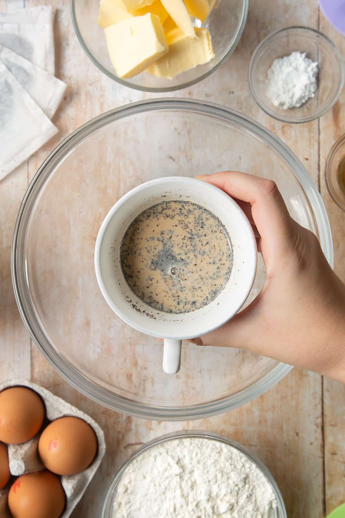 Overhead shot of a hand holding milk and tea in a mug