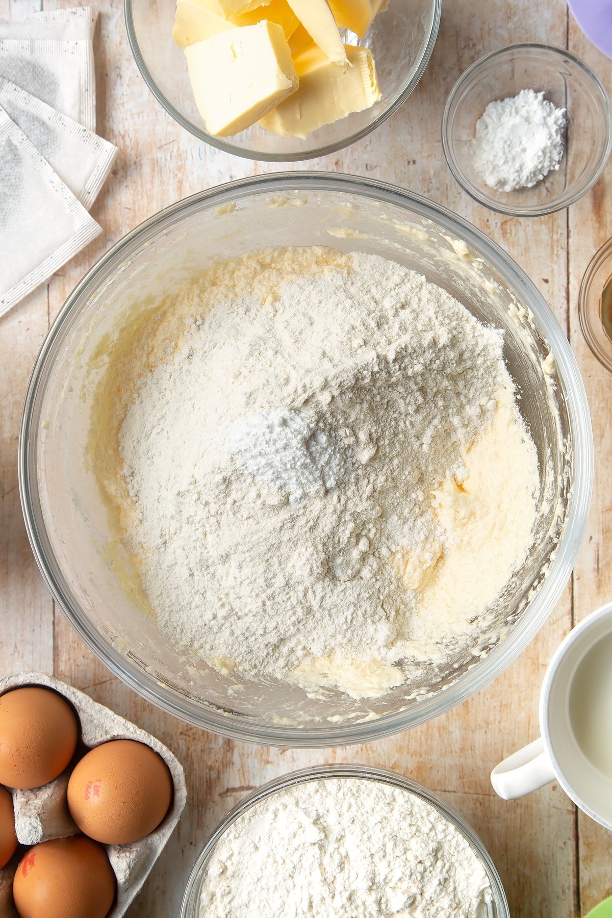 Overhead shot of clear bowl filled with flour and other ingredients for the cupcakes. 