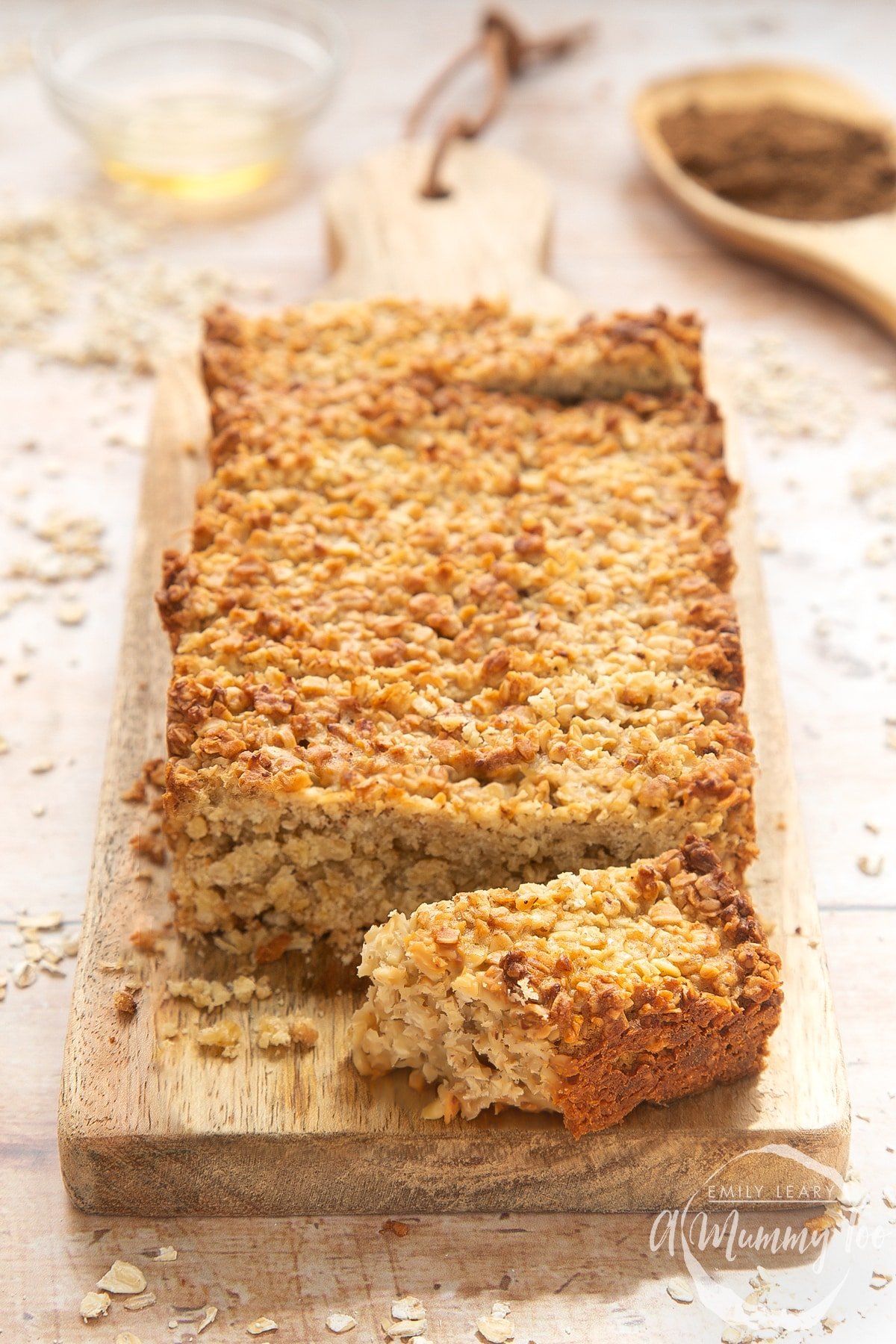 Overhead shot of half eaten vanilla oat flapjack served on a wooden plate with a mummy too logo in the lower-right corner