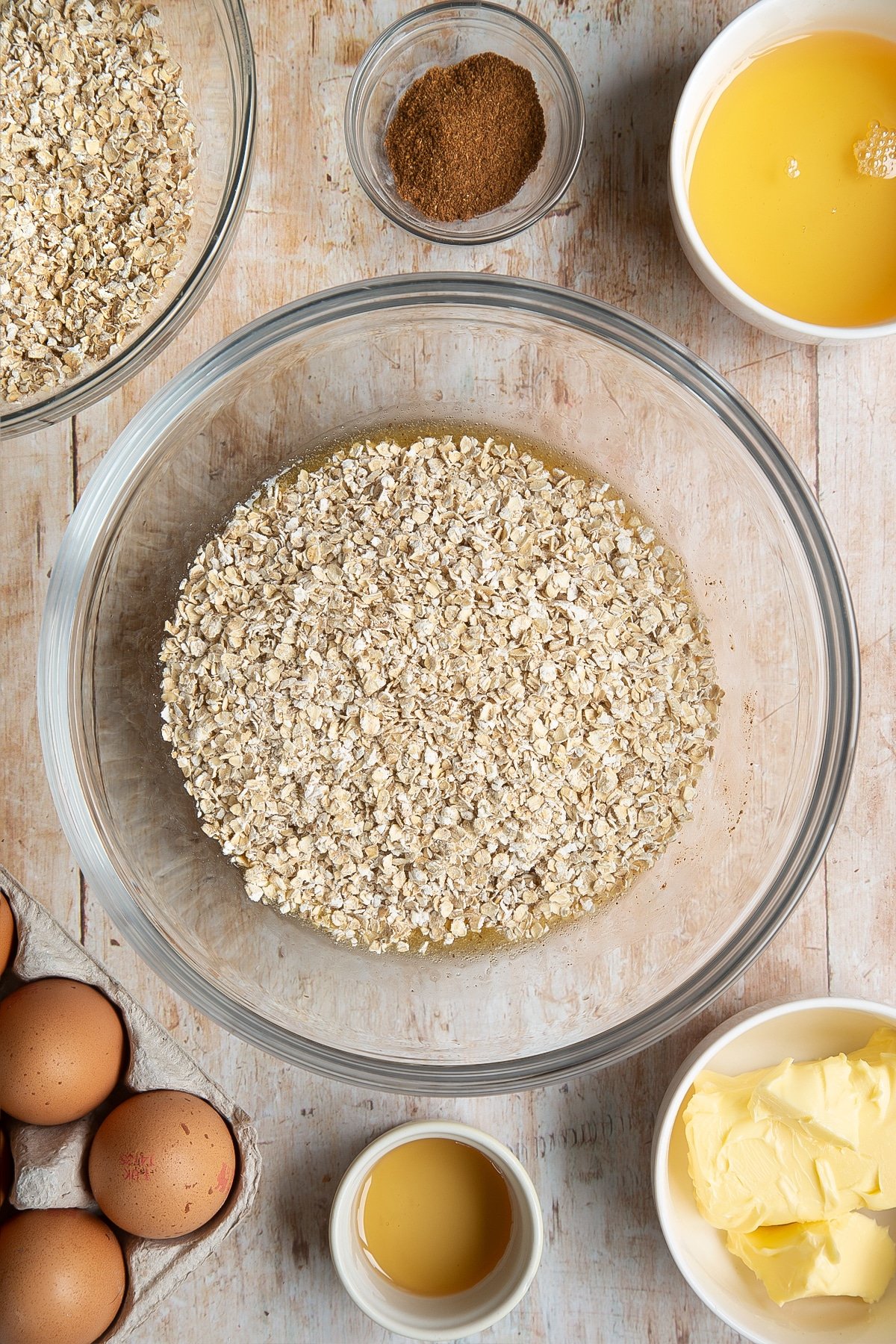 Overhead shot of oats on top of liquid mix in a clear mixing bowl 