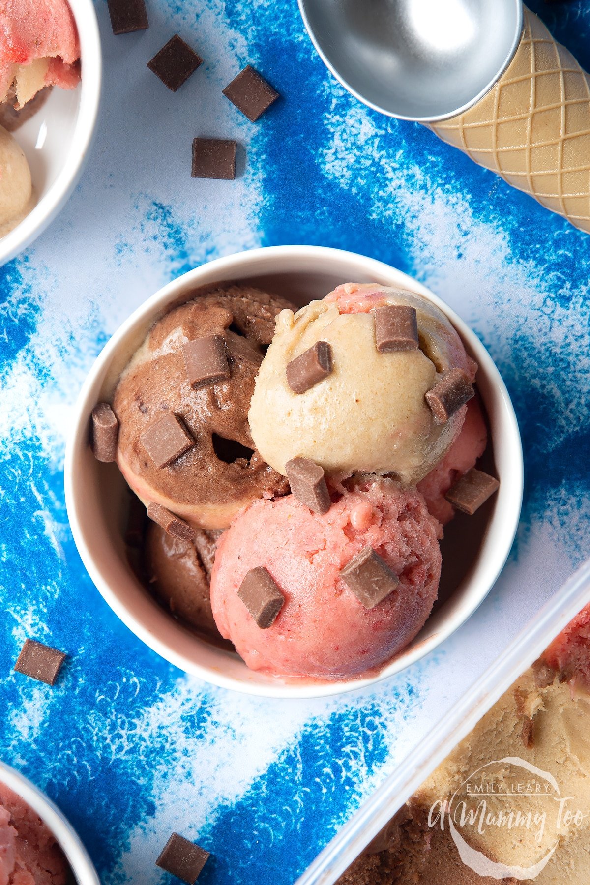 Close up of dairy-free Neapolitan ice cream served in a small white bowl, topped with chocolate chips.