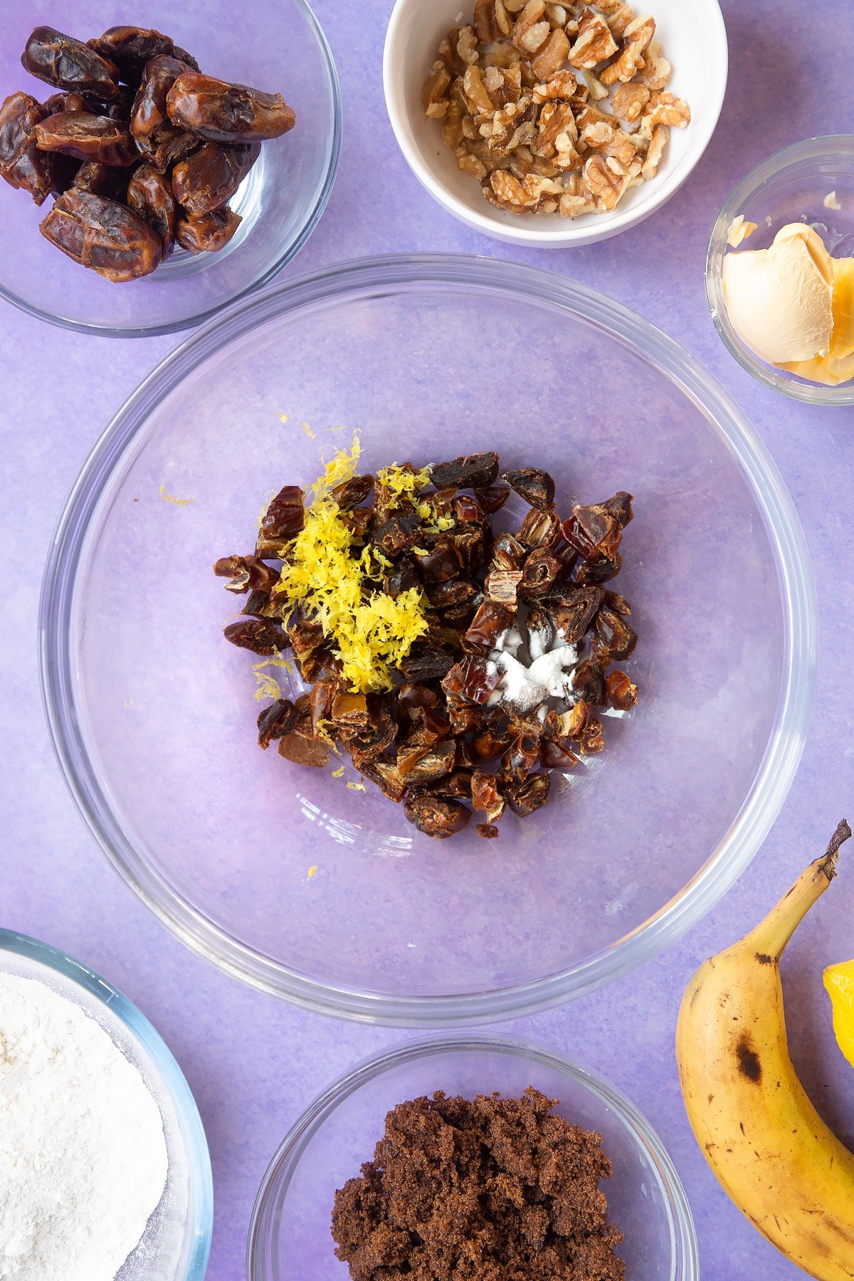 Overhead shot of a dates, bicarbonate of soda and lemon rind in large clear bowl