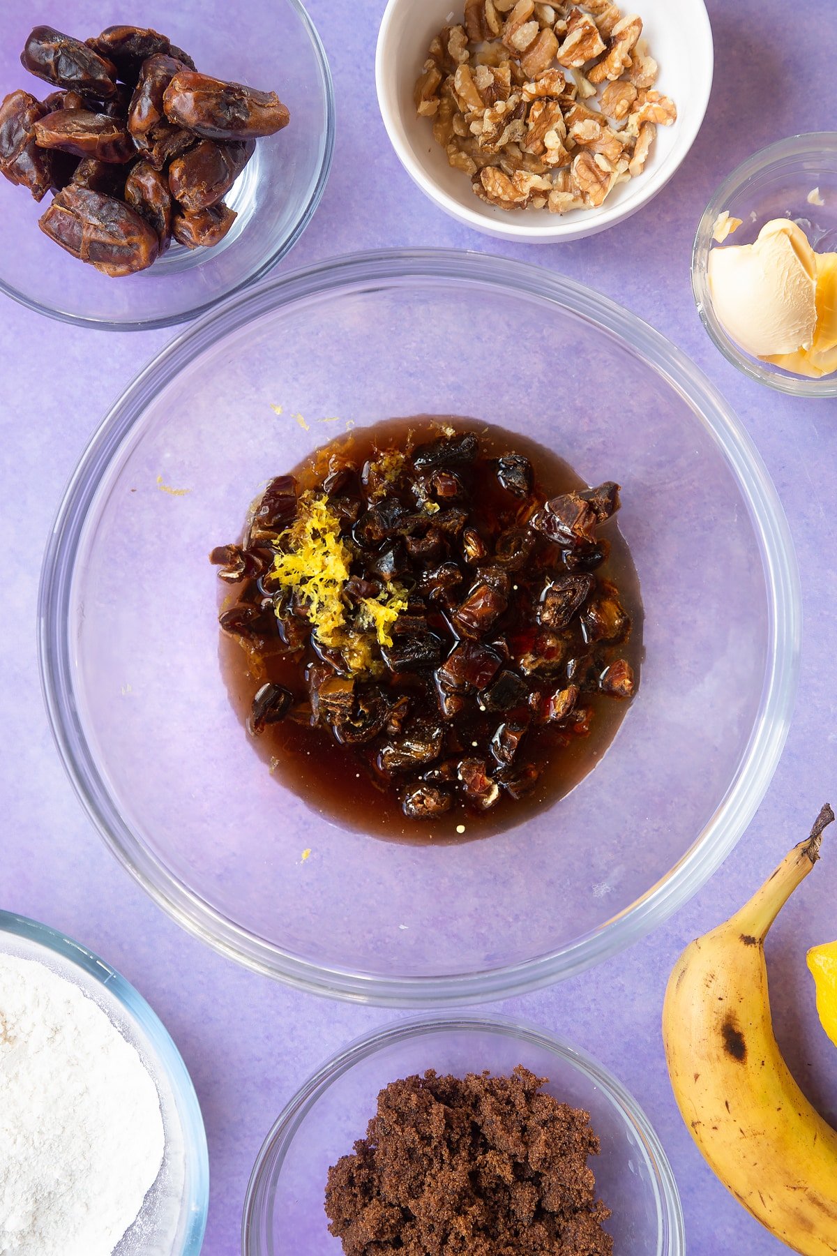 Overhead shot of a dates, bicarbonate of soda and lemon rind with tea in large clear bowl