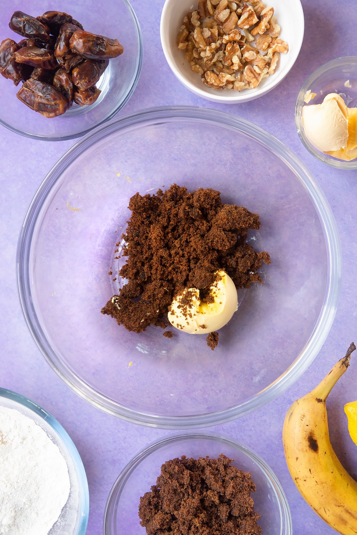 Overhead shot of a dates, bicarbonate of soda and lemon rind soaked in tea in large clear bowl