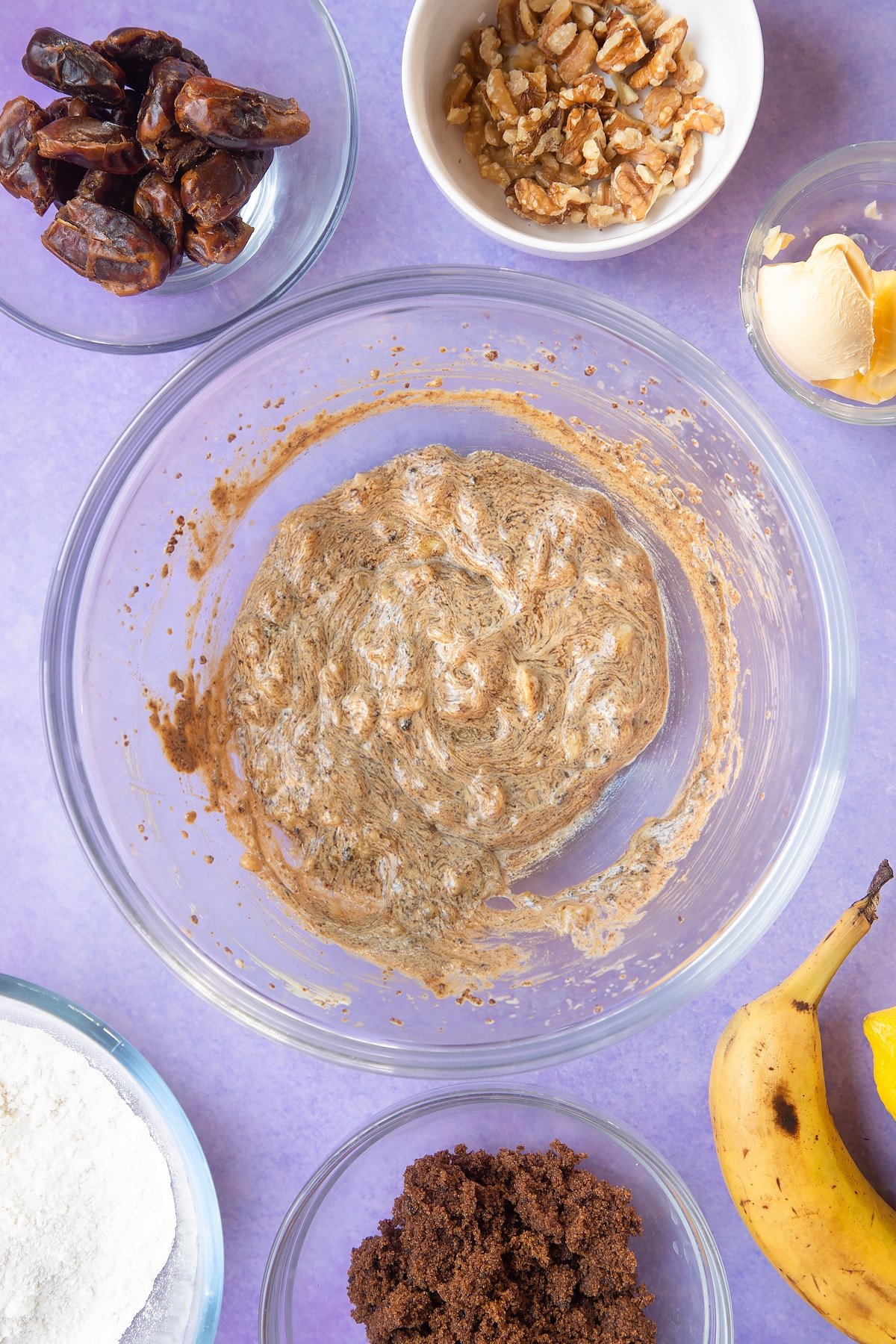 Overhead shot of whipped margarine mix topped mashed bananas in a large clear bowl