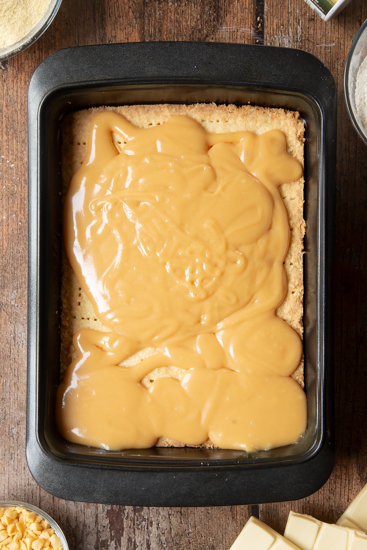 Pouring the caramel ontop the cool biscuit covering. 