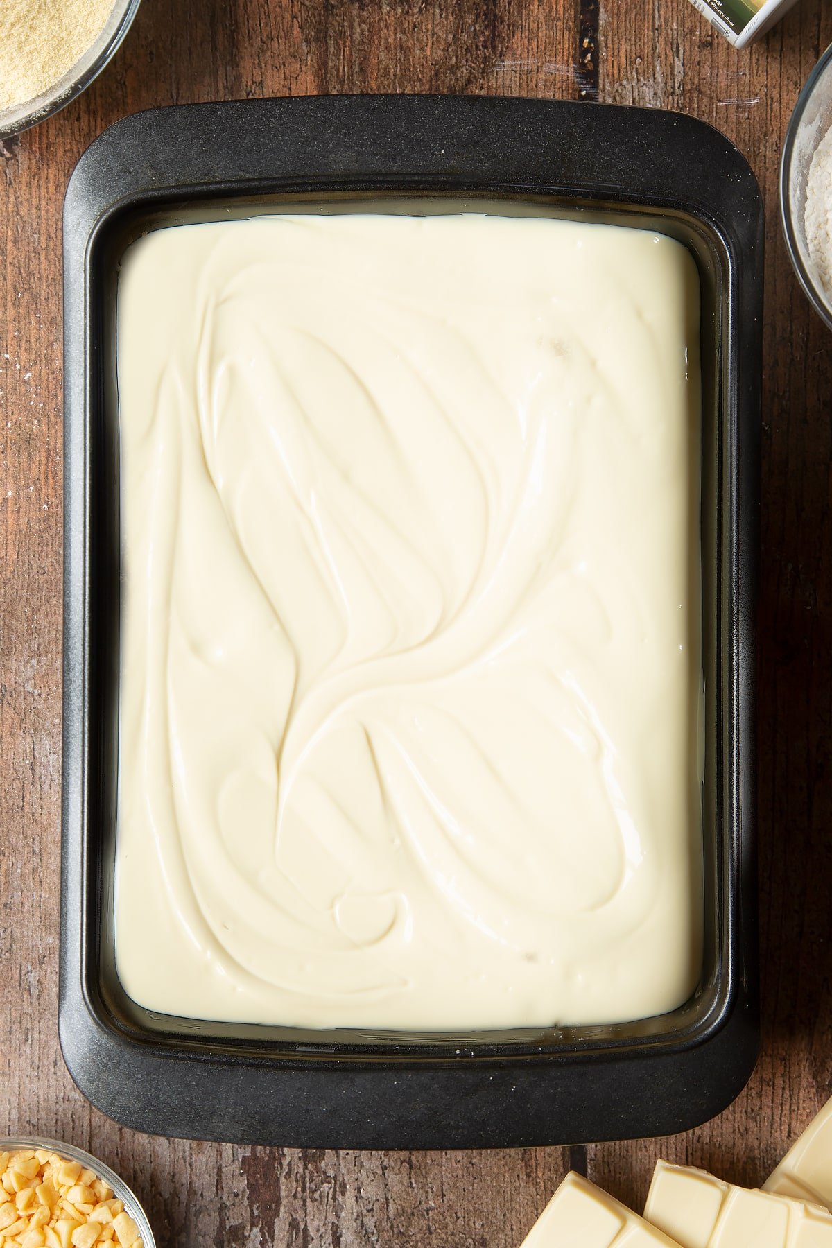 Overhead shot of the whte chocolate being poured over the caramel inside the cake tin. 