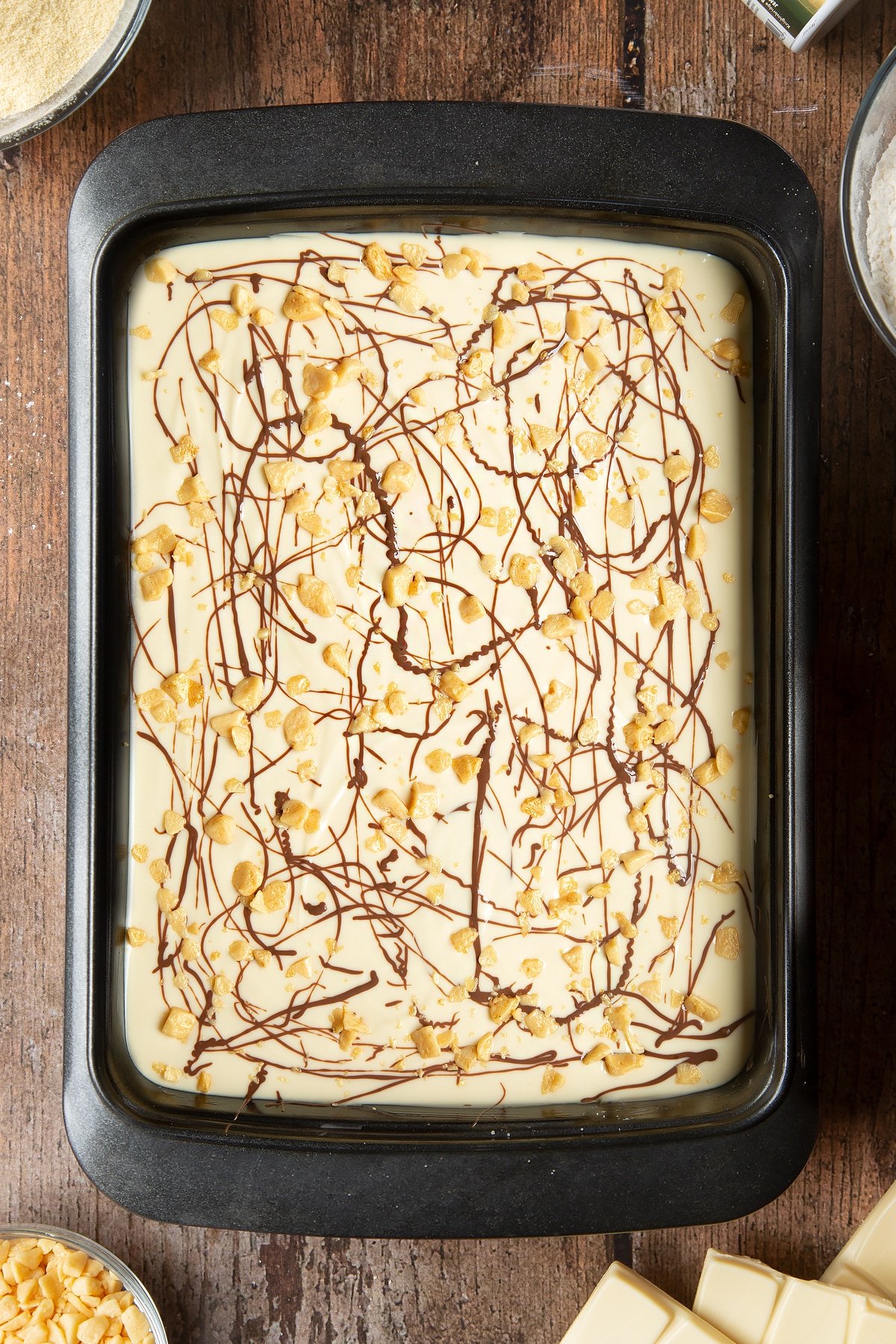 Overhead shot of the honeycomb added to the milk chocolate drizzle inside the cake tin. 