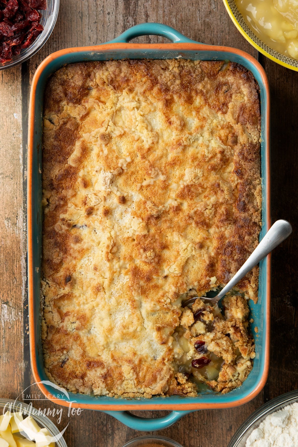 Apple cranberry dump cake in a tray. A spoon delves into the cake.