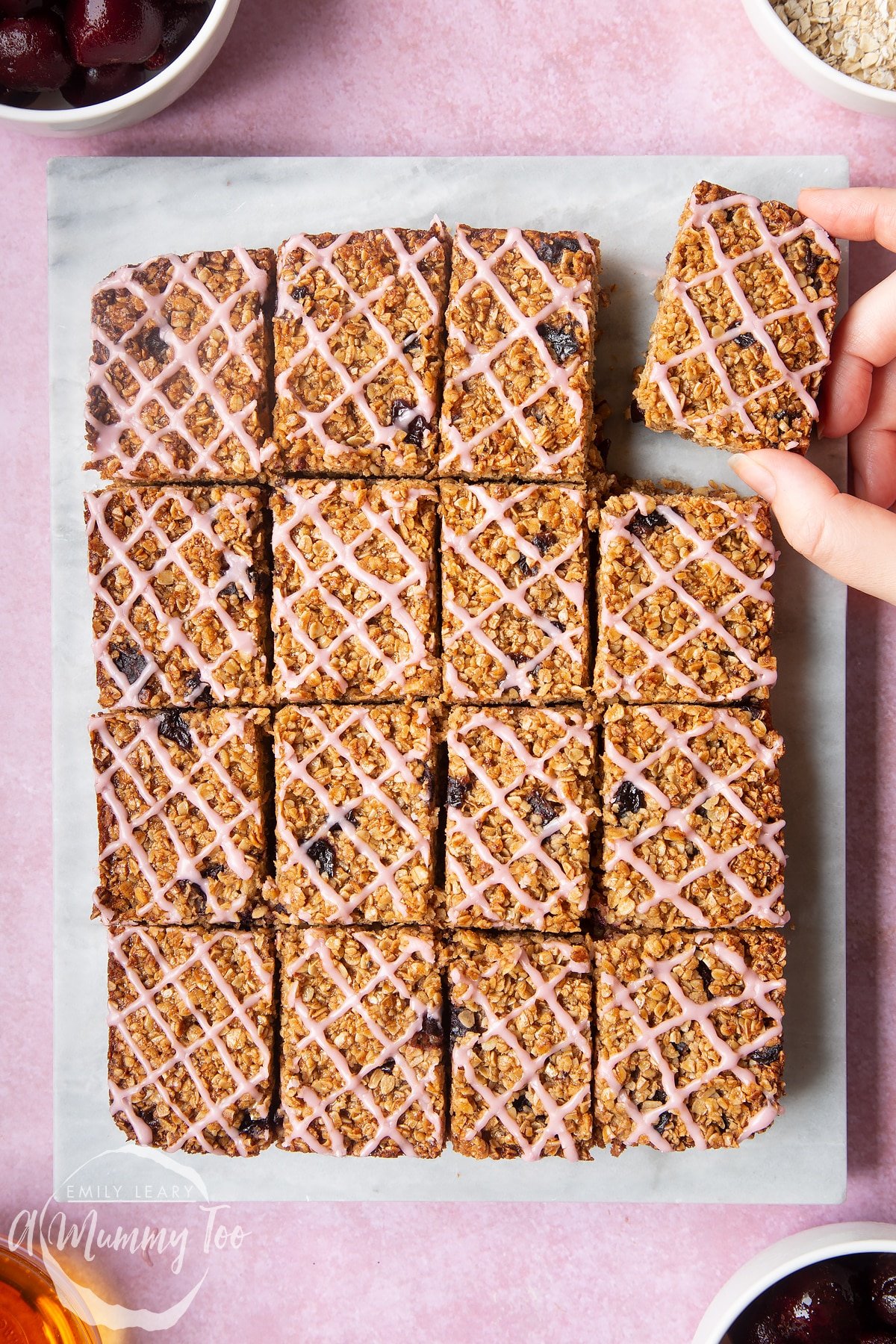 Overhead shot of a hand removing a cherry flapjack served on a white plate with a mummy too logo in the lower-left corner