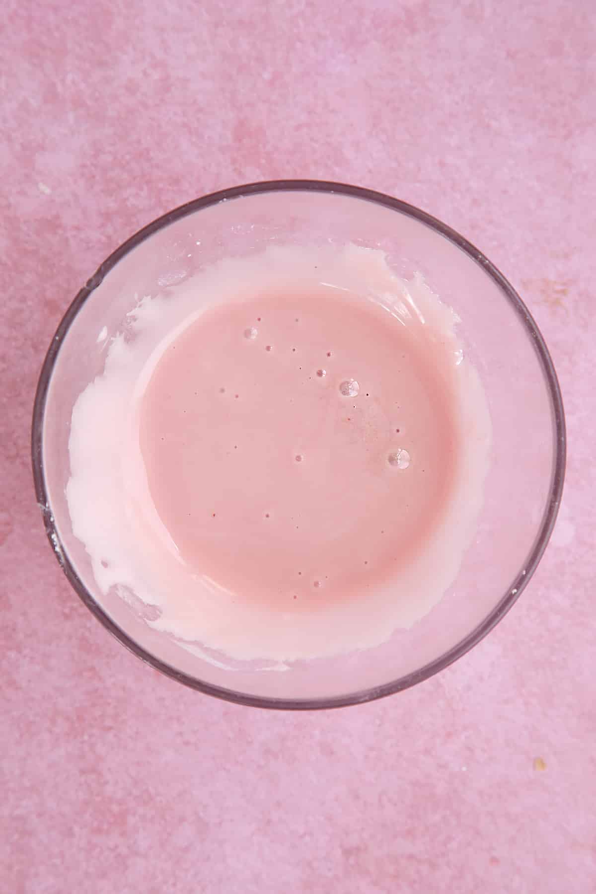 Overhead shot of pink liquid icing in a small bowl