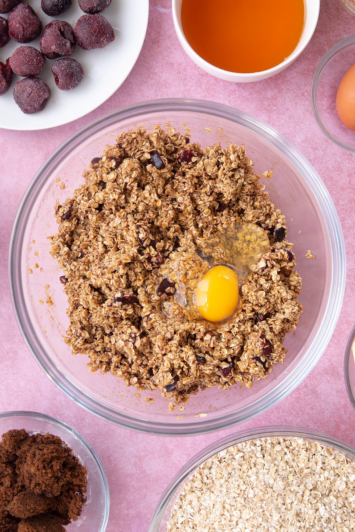 Overhead shot of oats mix and an egg in a large clear bowl