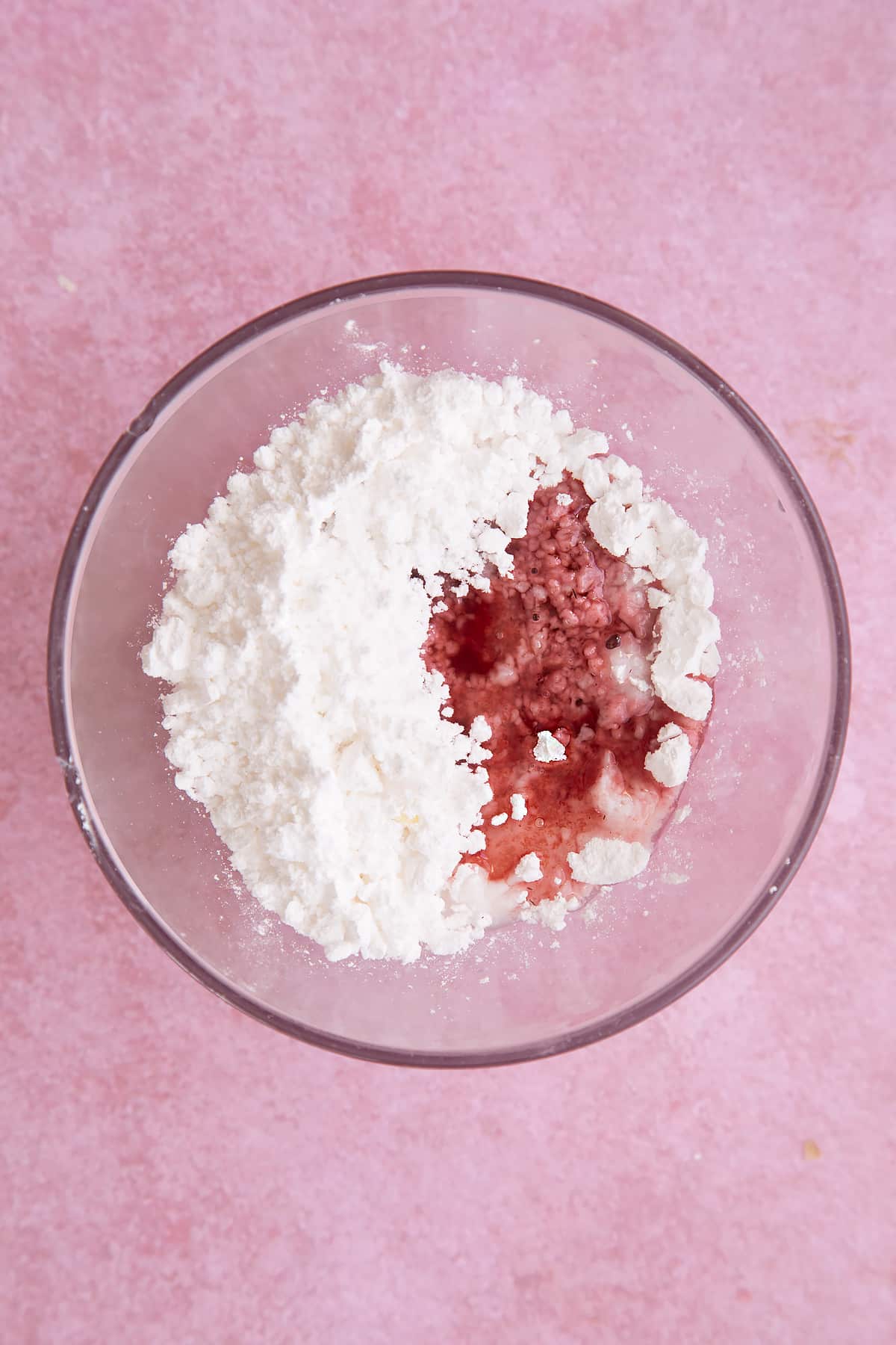 Overhead shot of icing sugar and cherry juice in a small clear bowl
